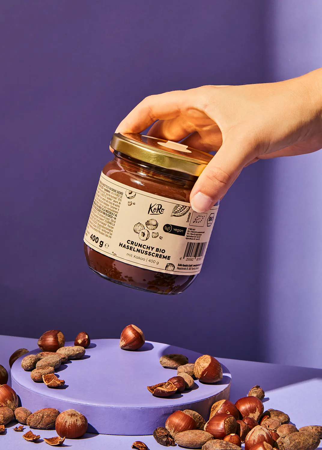 une personne tient un bocal de crème aux noisettes crunchy bio