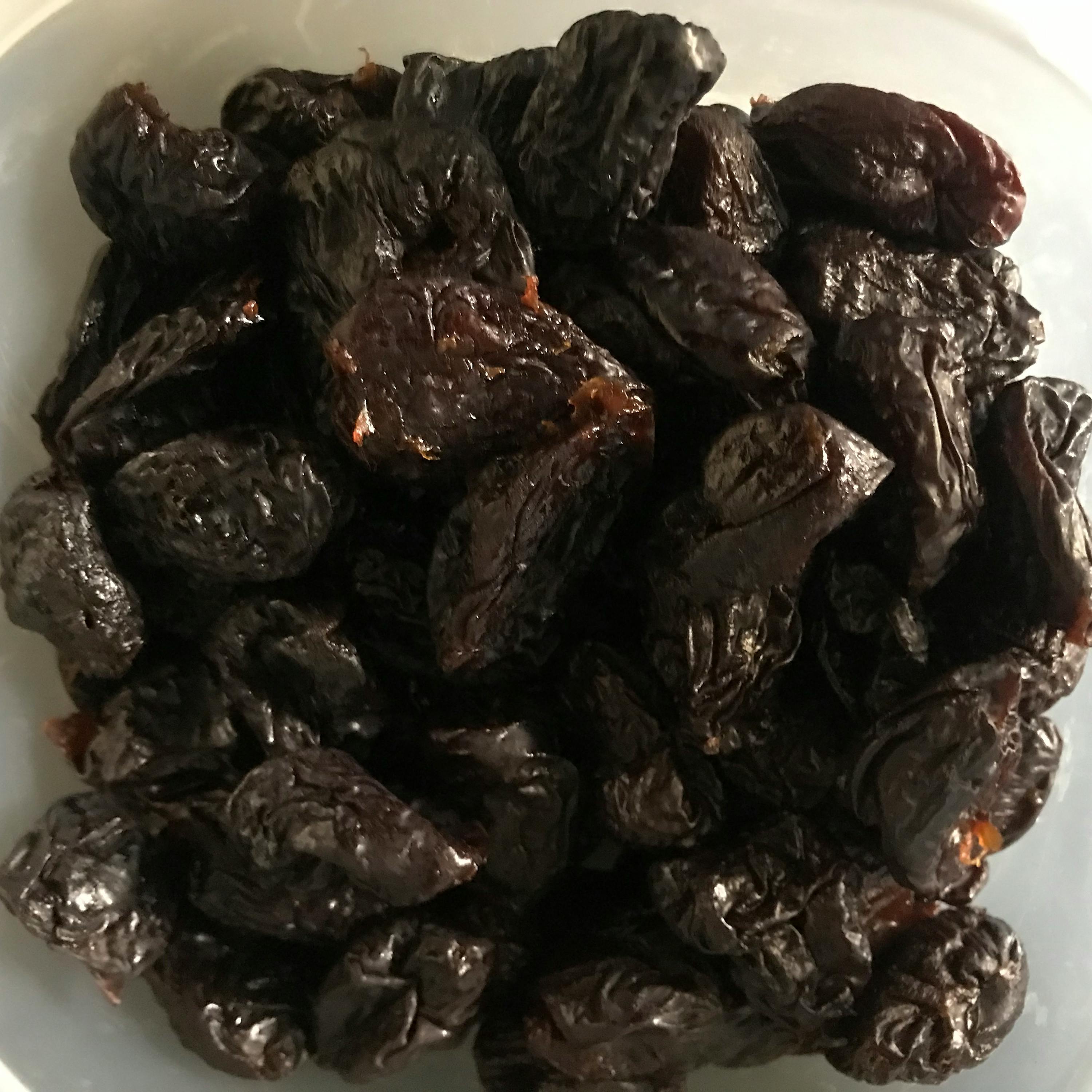 una ciotola bianca piena di prugne secche nere