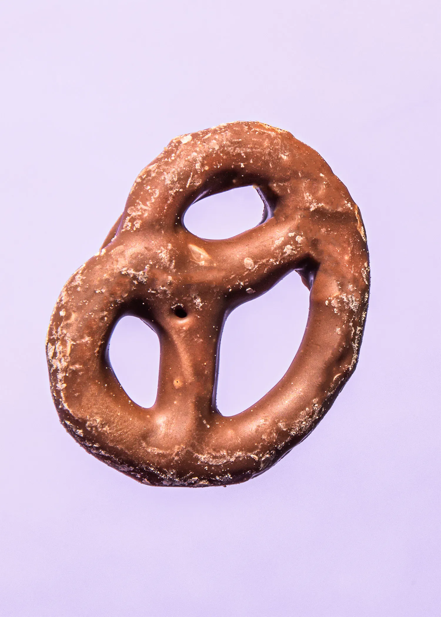a chocolate covered pretzel on a purple surface