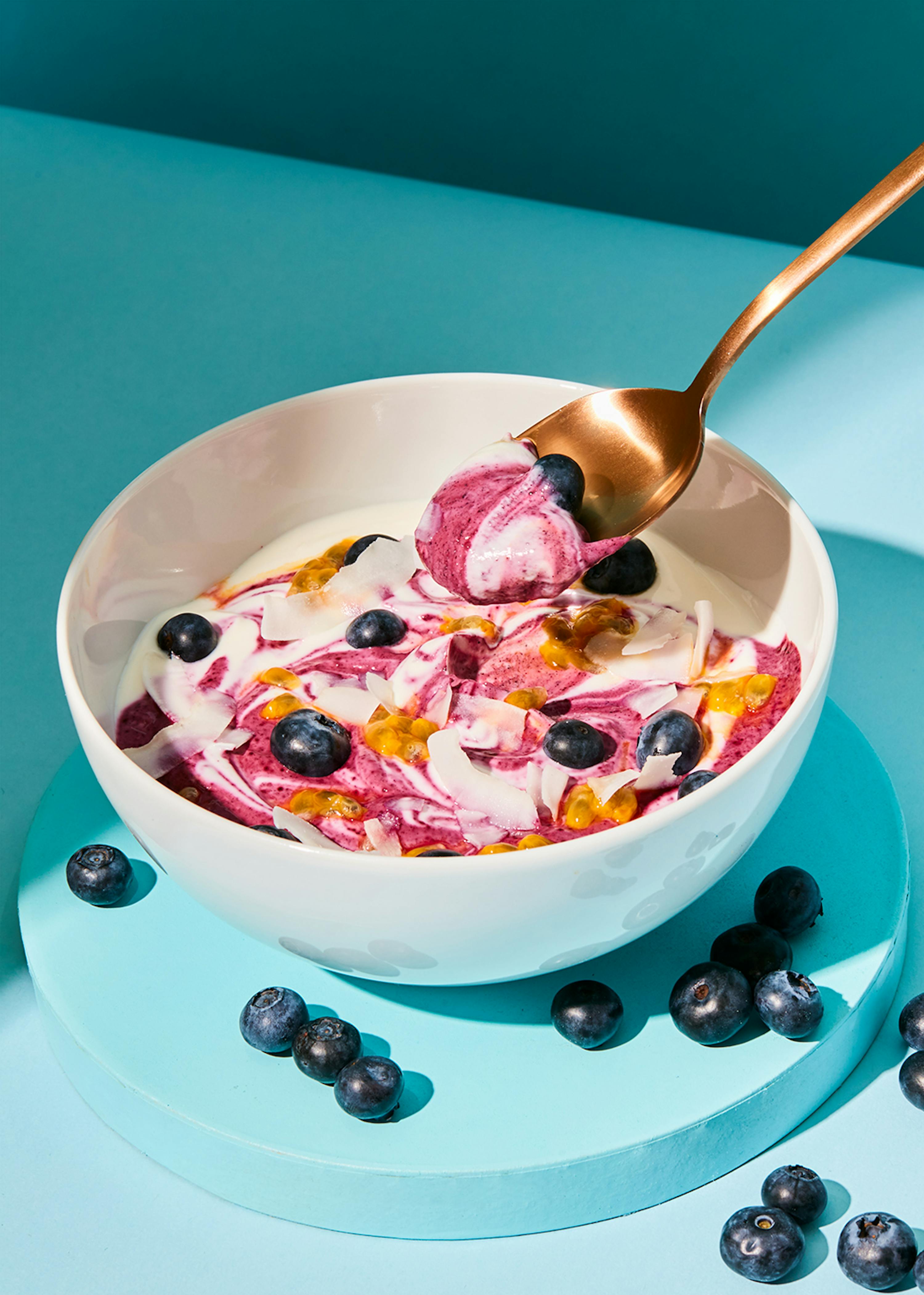 a bowl of cereal with blueberries and yogurt with a spoon in it
