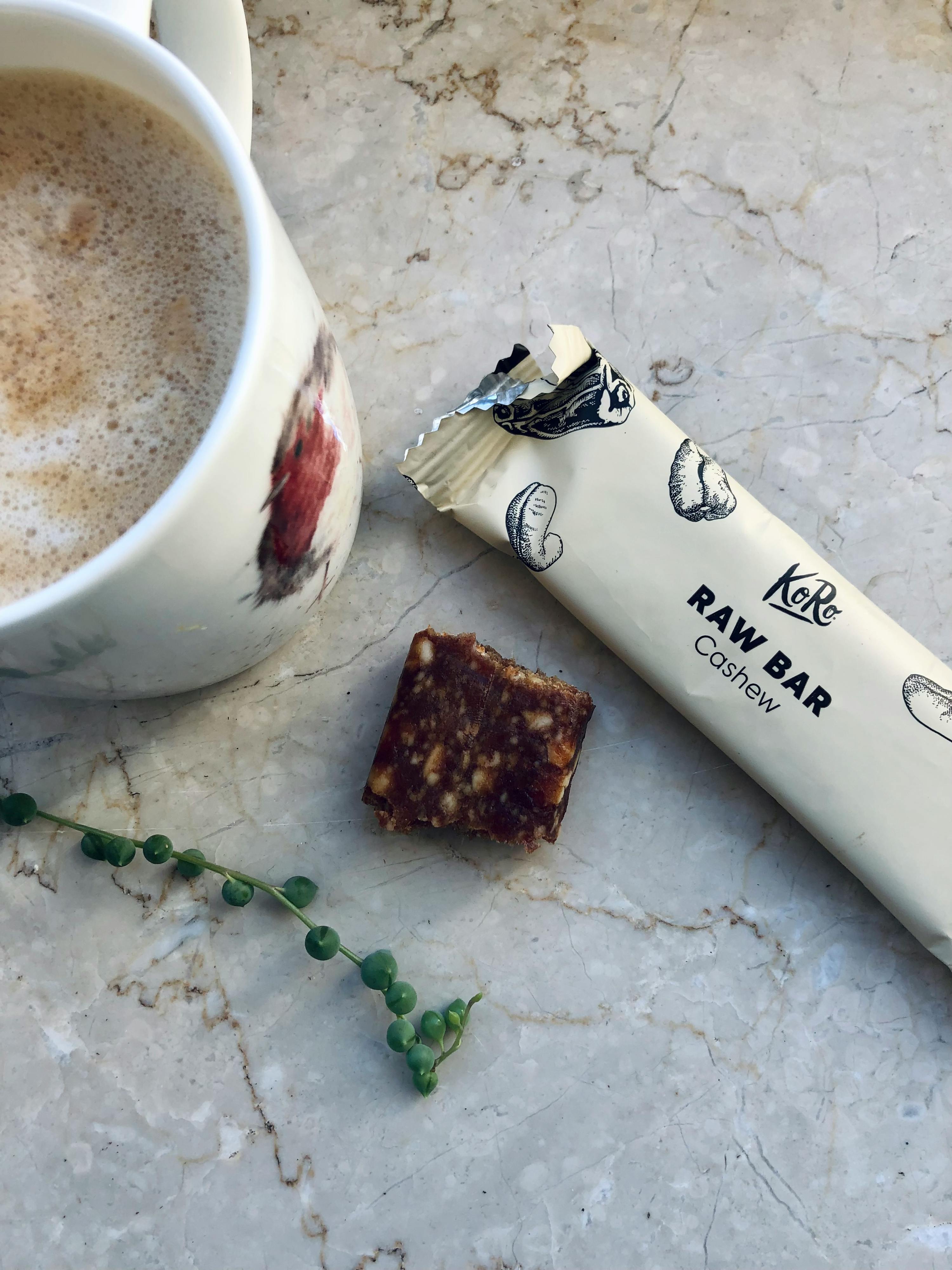 una barretta raw cashew è seduta accanto a una tazza di caffè