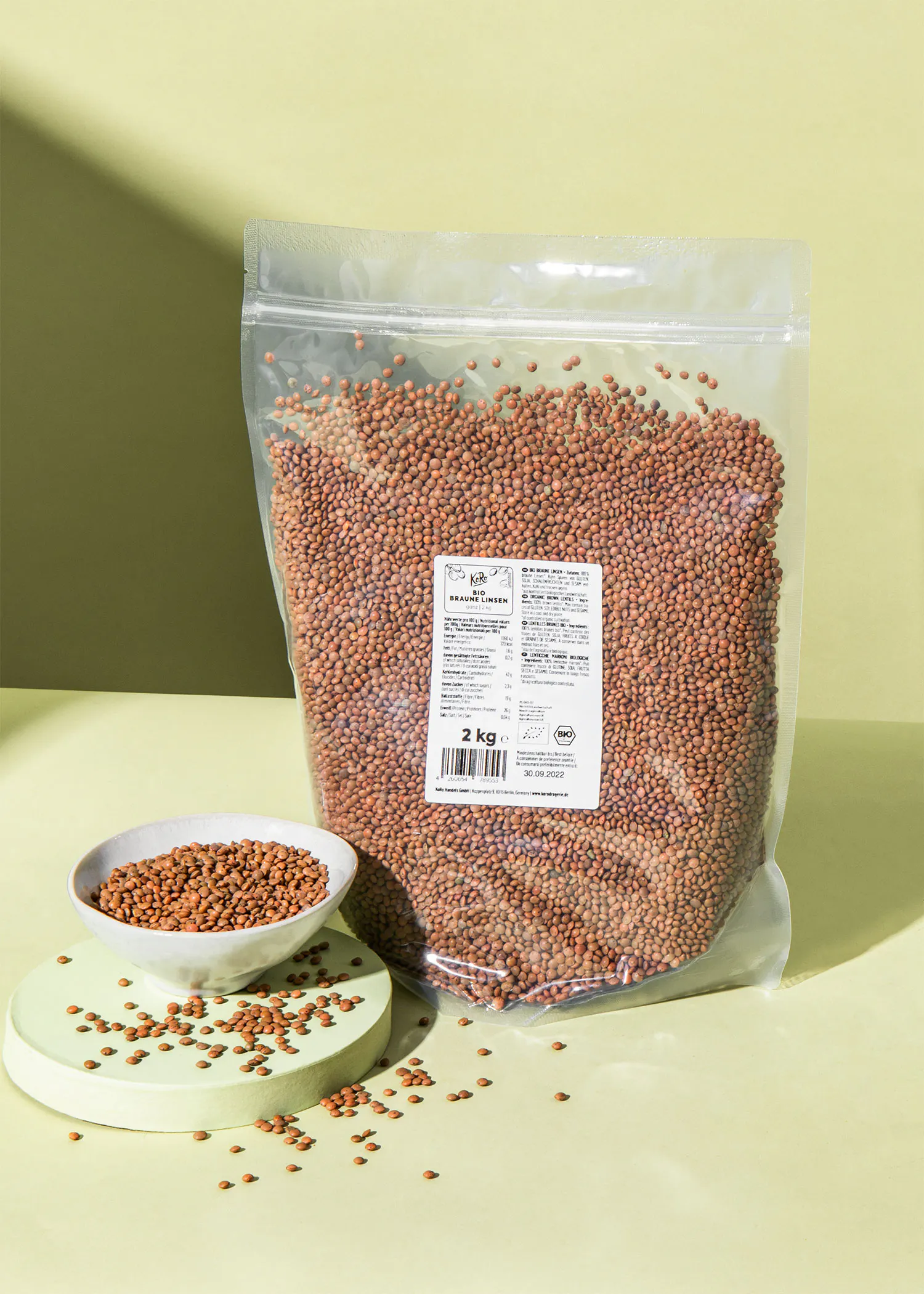 a 2 kg bag of beans sits on a table next to a bowl of beans