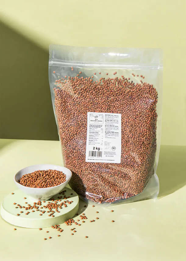 a 2 kg bag of beans sits on a table next to a bowl of beans