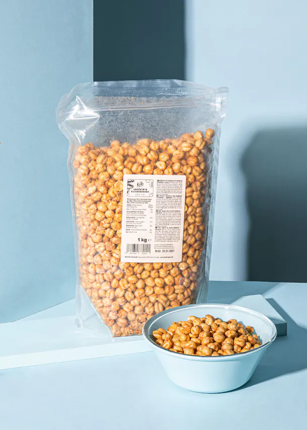 eine Tüte gesalzener Erdnüsse neben einer Schüssel Erdnüsse