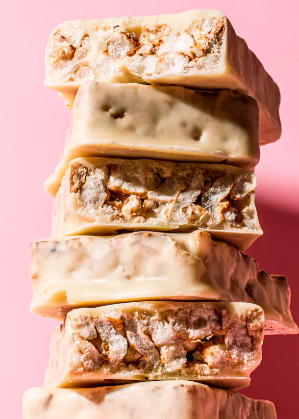 une pile de barres de chocolat blanc sur fond rose