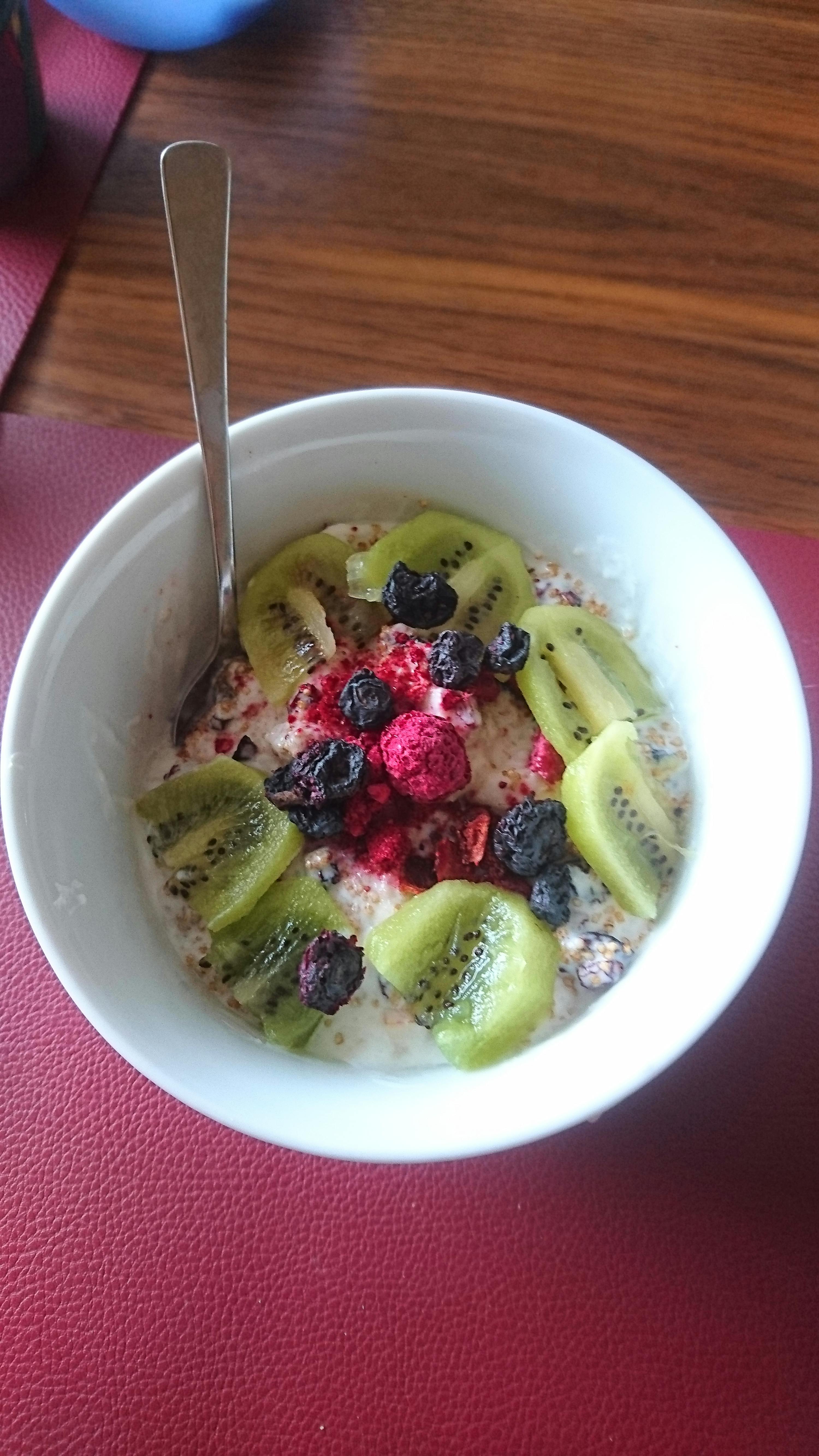 a bowl of oatmeal with kiwi slices blueberries and raspberries