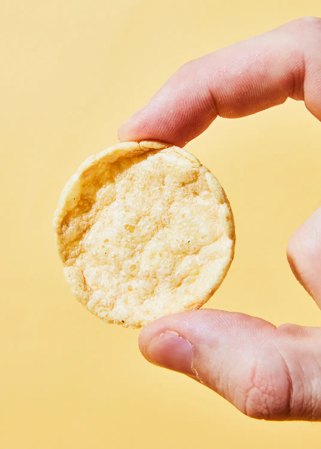 une personne tient une tranche de chips dans sa main