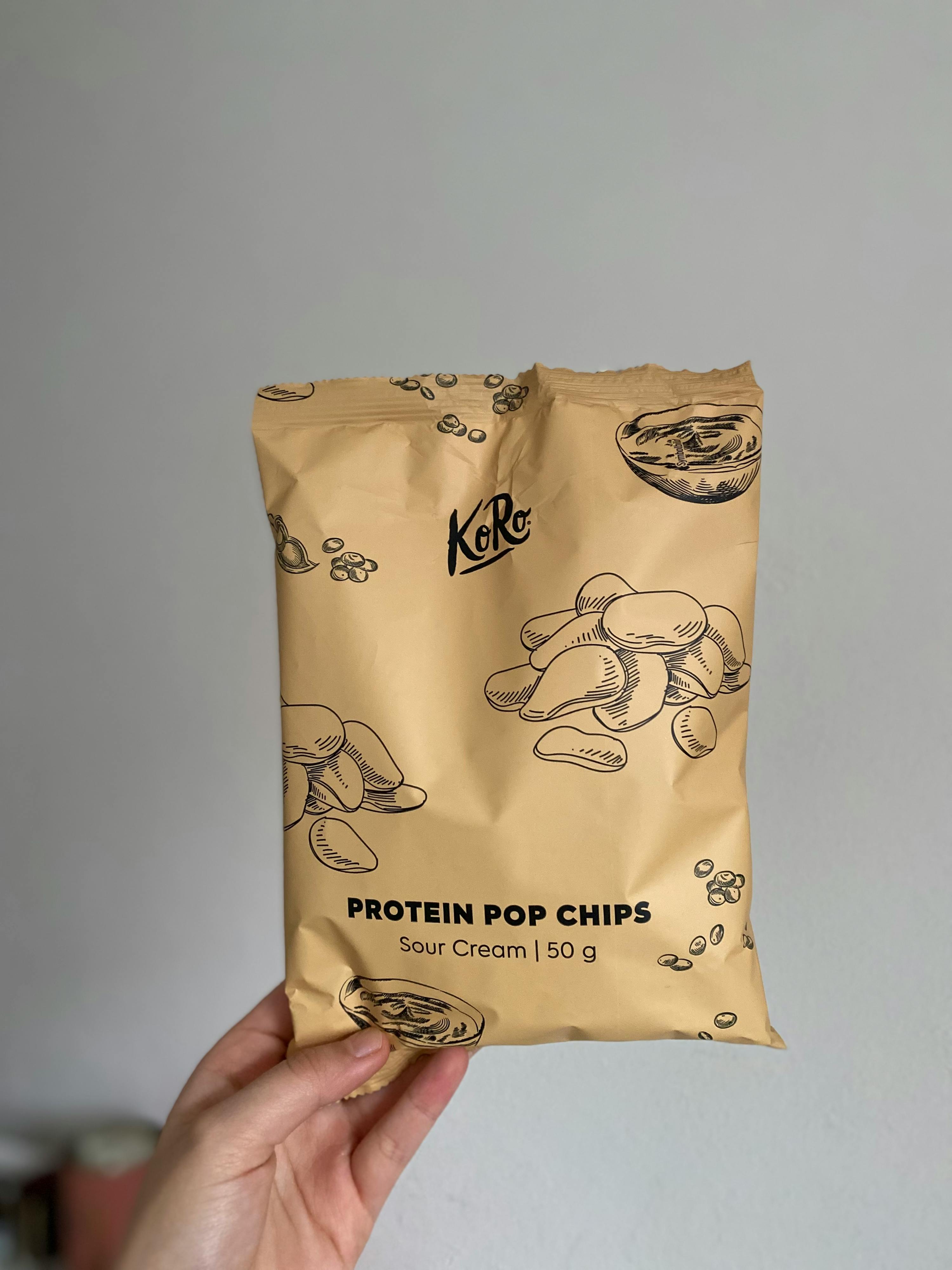 a person is holding a bag of protein pop chips sour cream