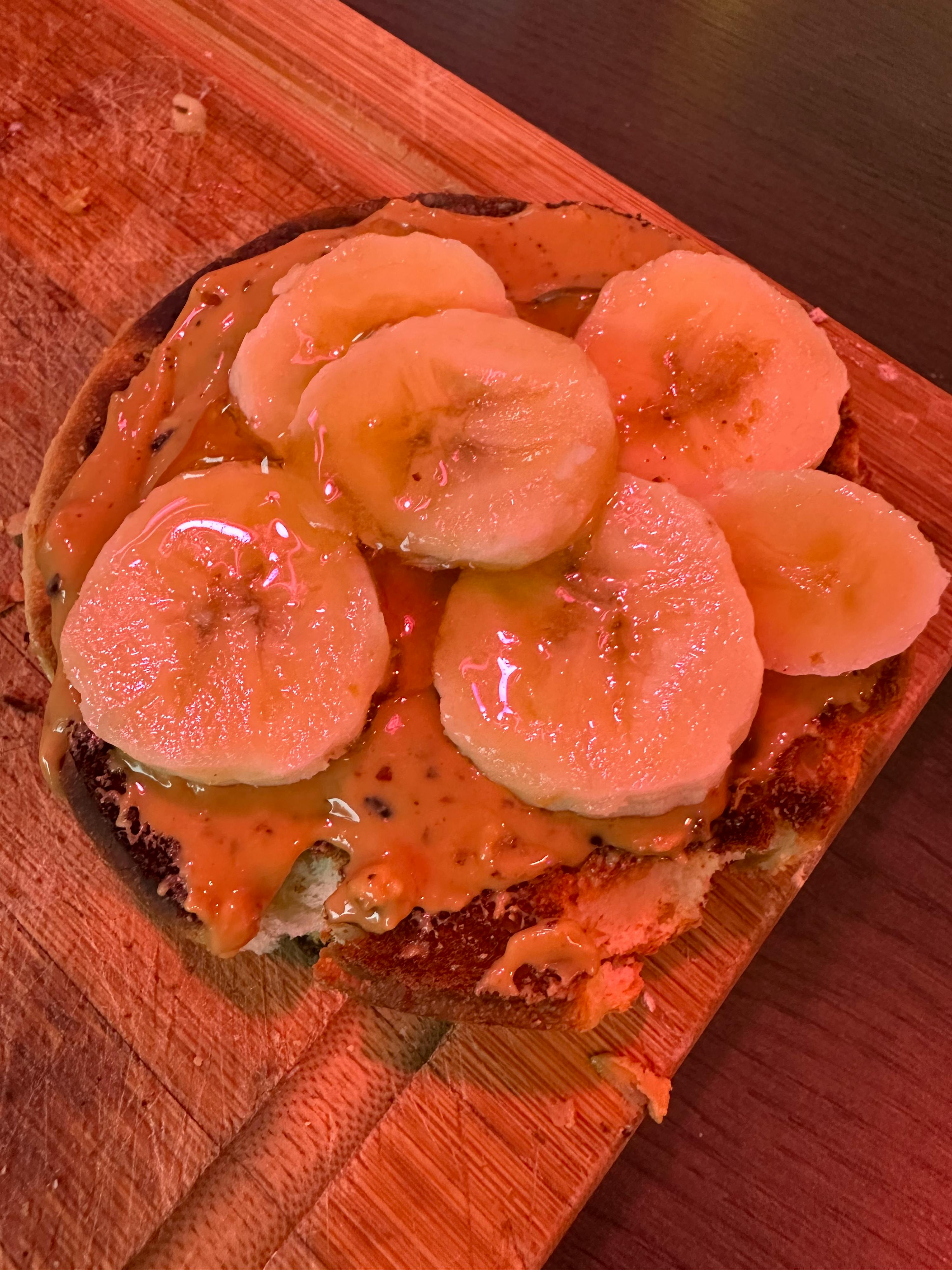 un bagel con burro di arachidi e banane su un tagliere di legno