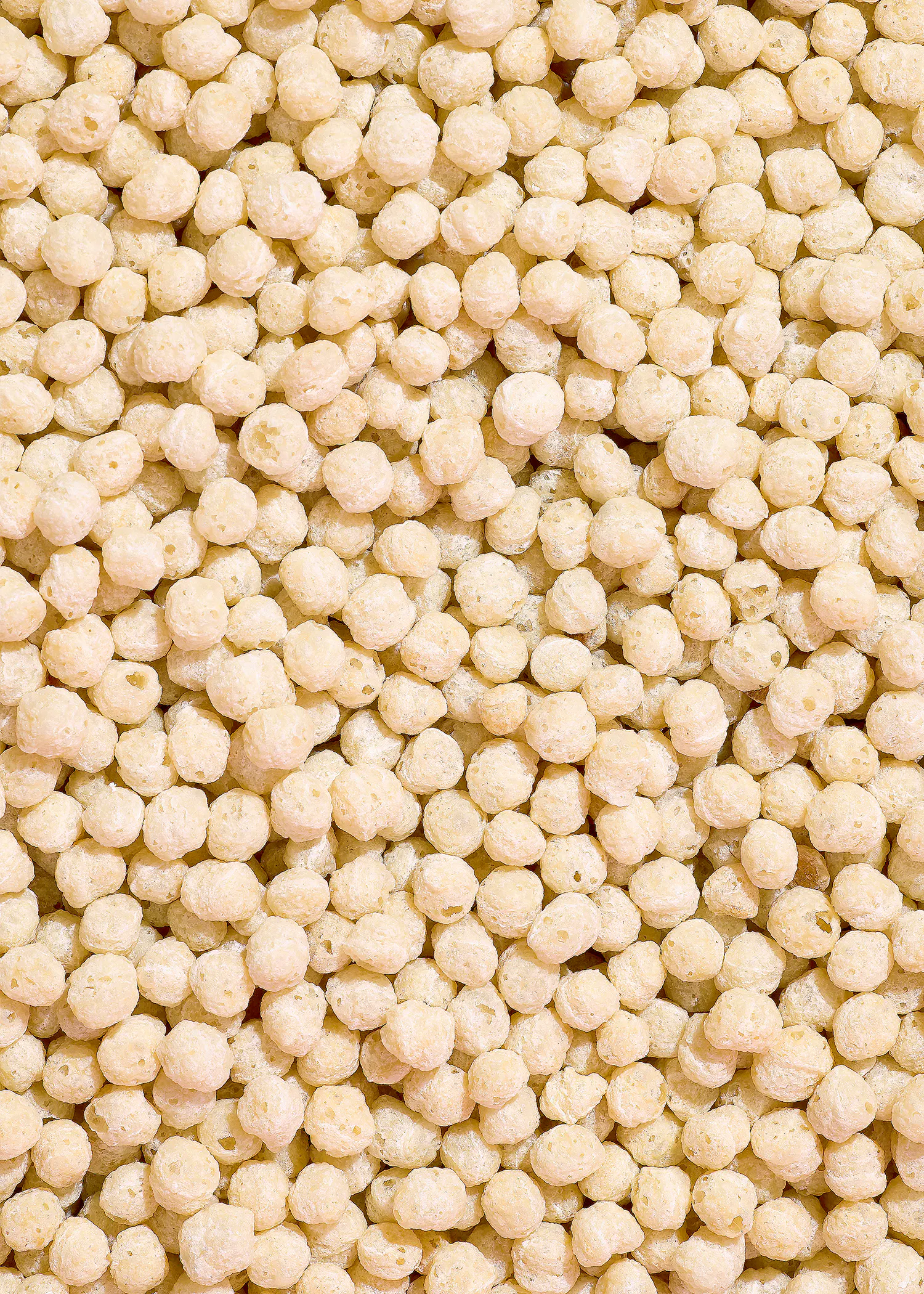 gros plan sur une multitude de petites boules de céréales soufflées de couleur crème, remplissant tout le cadre.