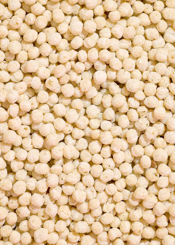 gros plan sur une multitude de petites boules de céréales soufflées de couleur crème, remplissant tout le cadre.