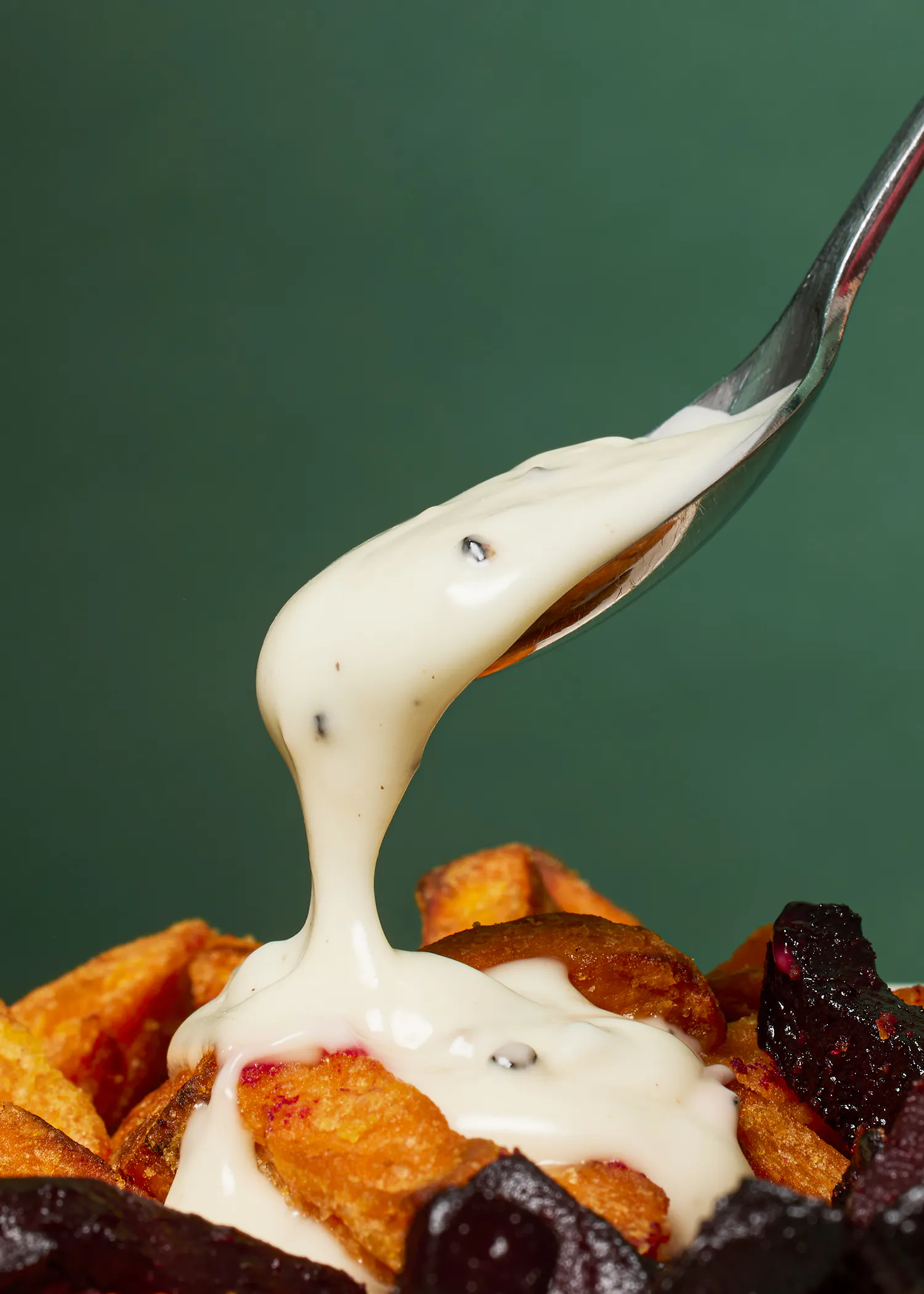 une cuillère remplie de sauce blanche sur une assiette de frites