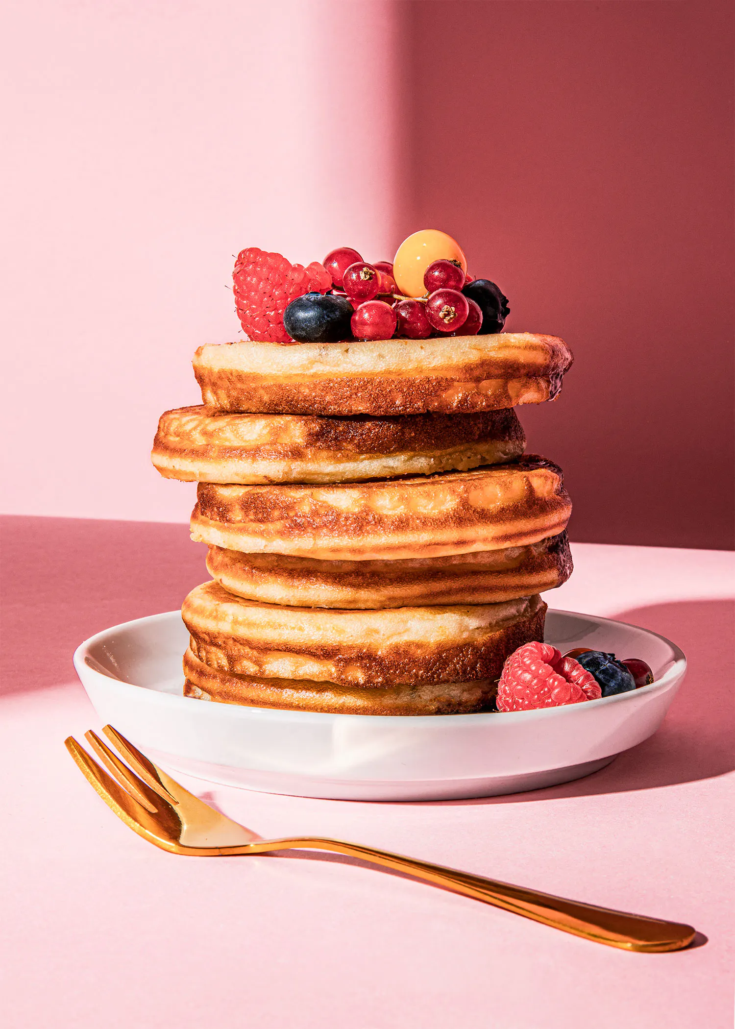 a stack of pancakes with berries on top on a plate with a fork