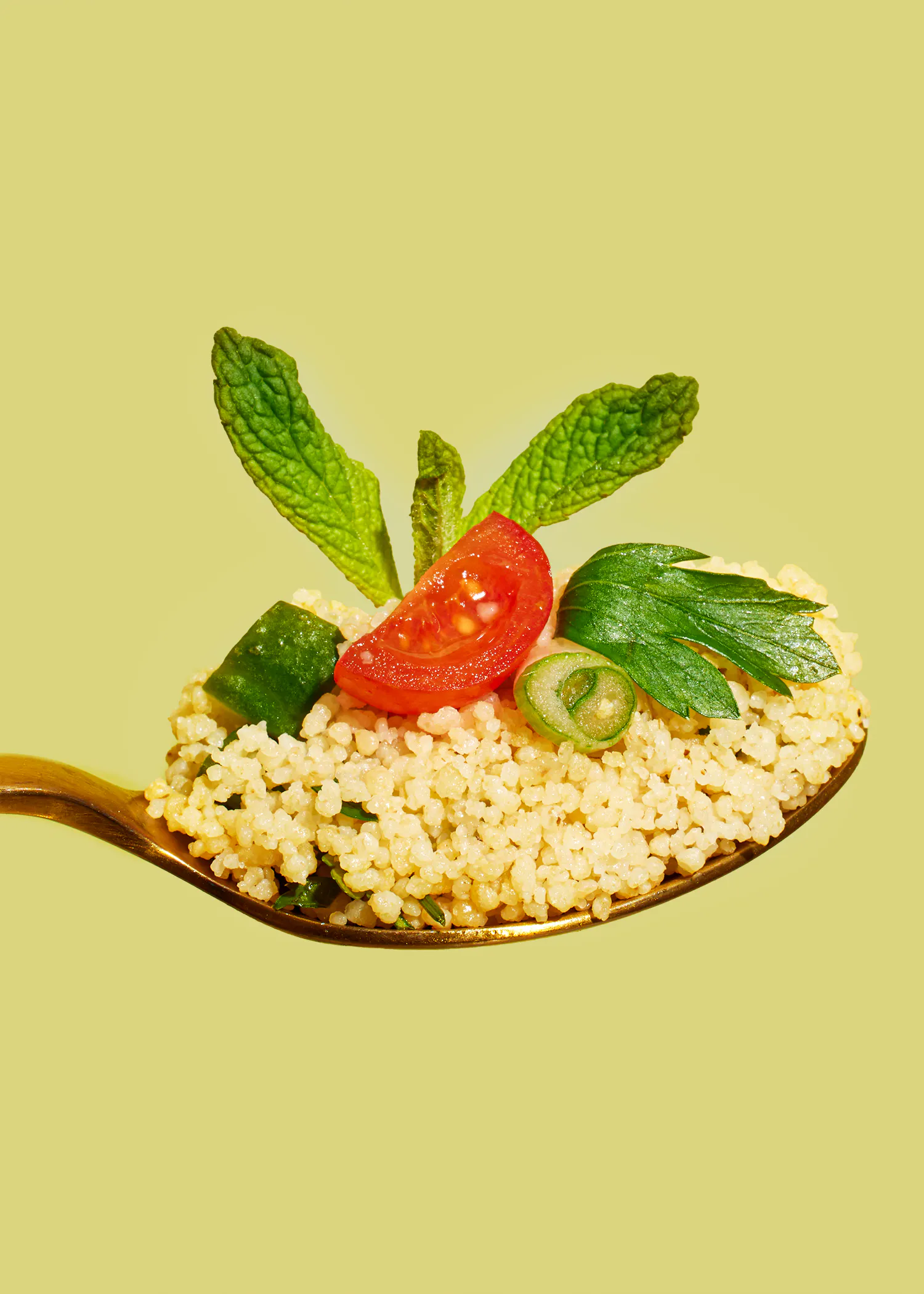 une cuillère remplie de riz avec des tomates et des concombres