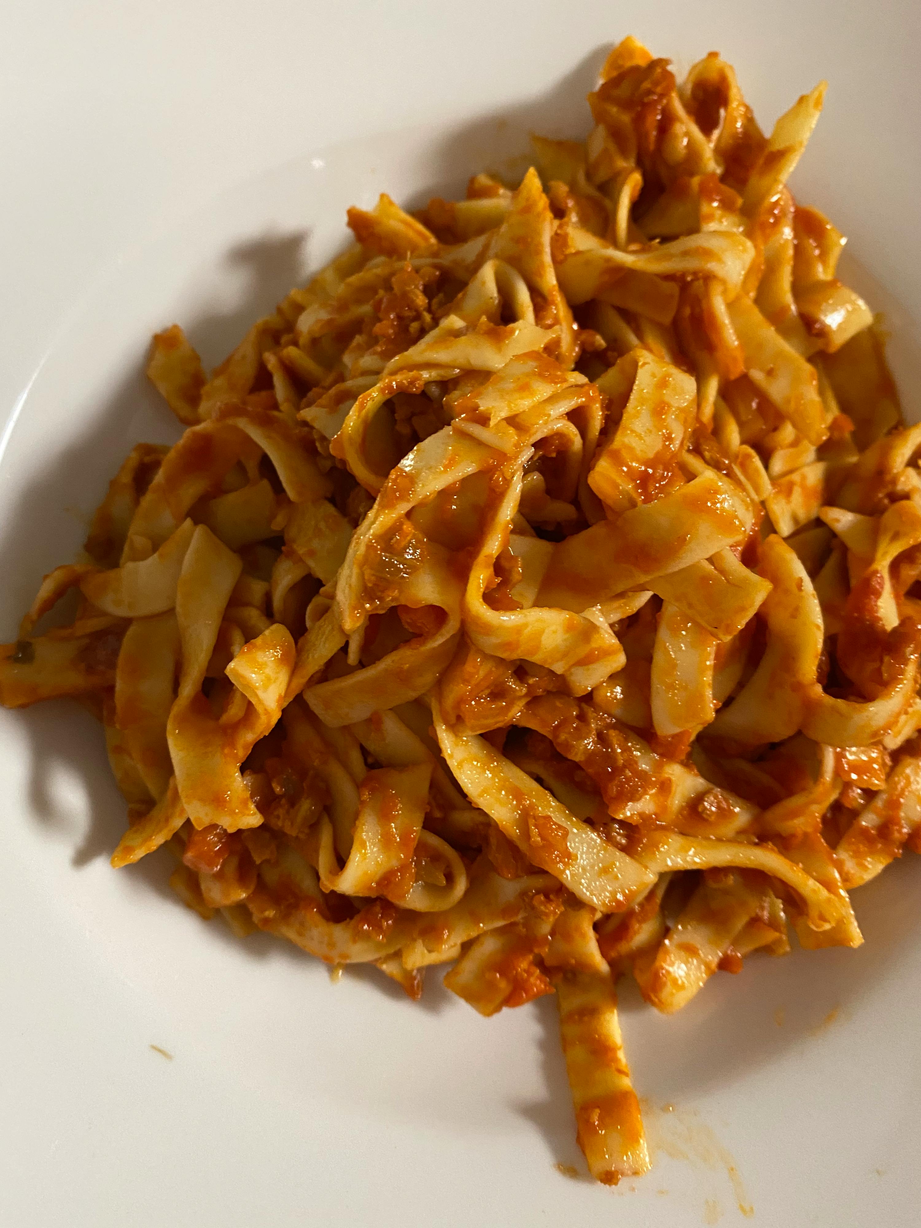 une assiette blanche remplie de nouilles et de sauce