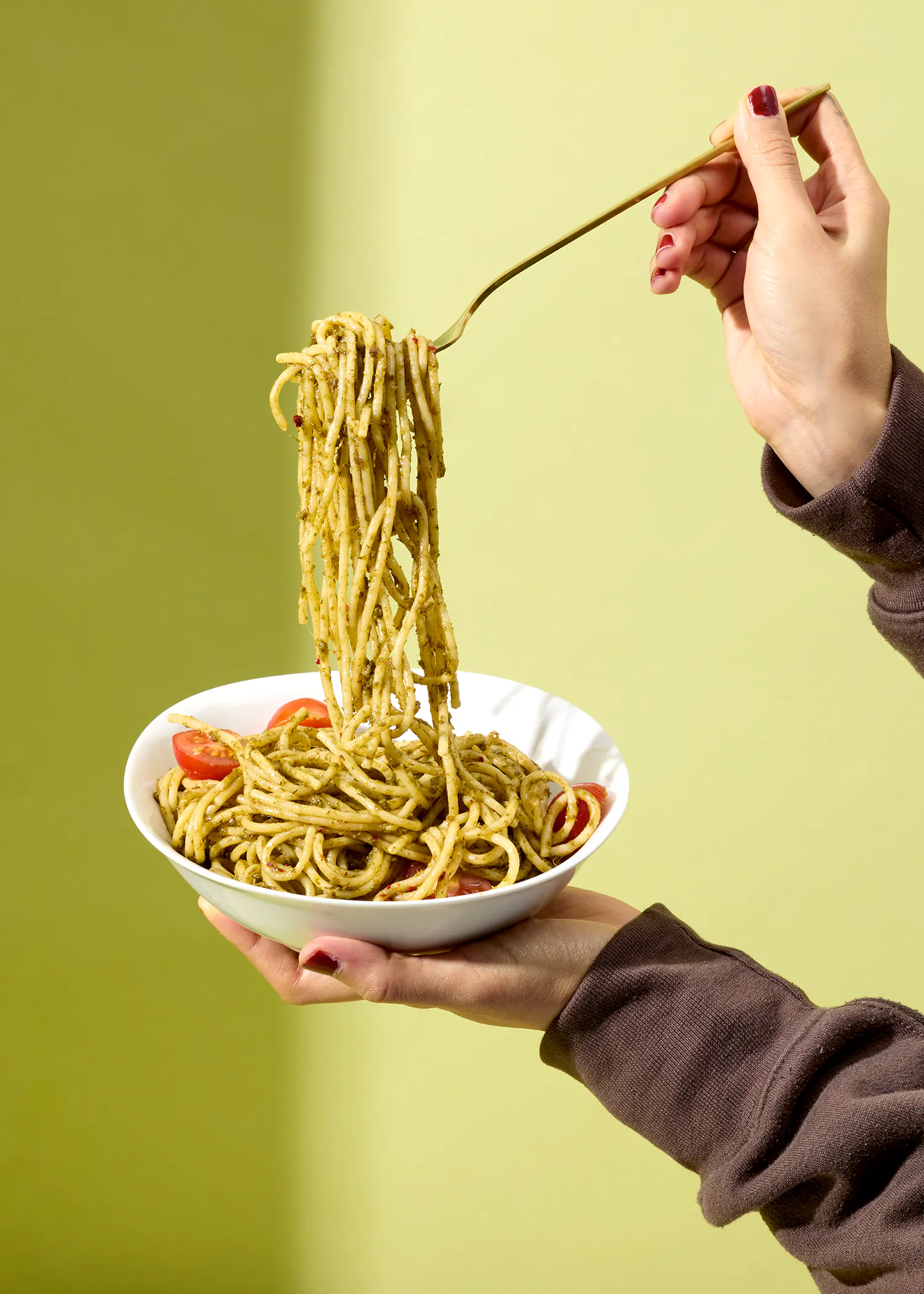 eine Person hält einen Teller Nudeln mit einer Gabel