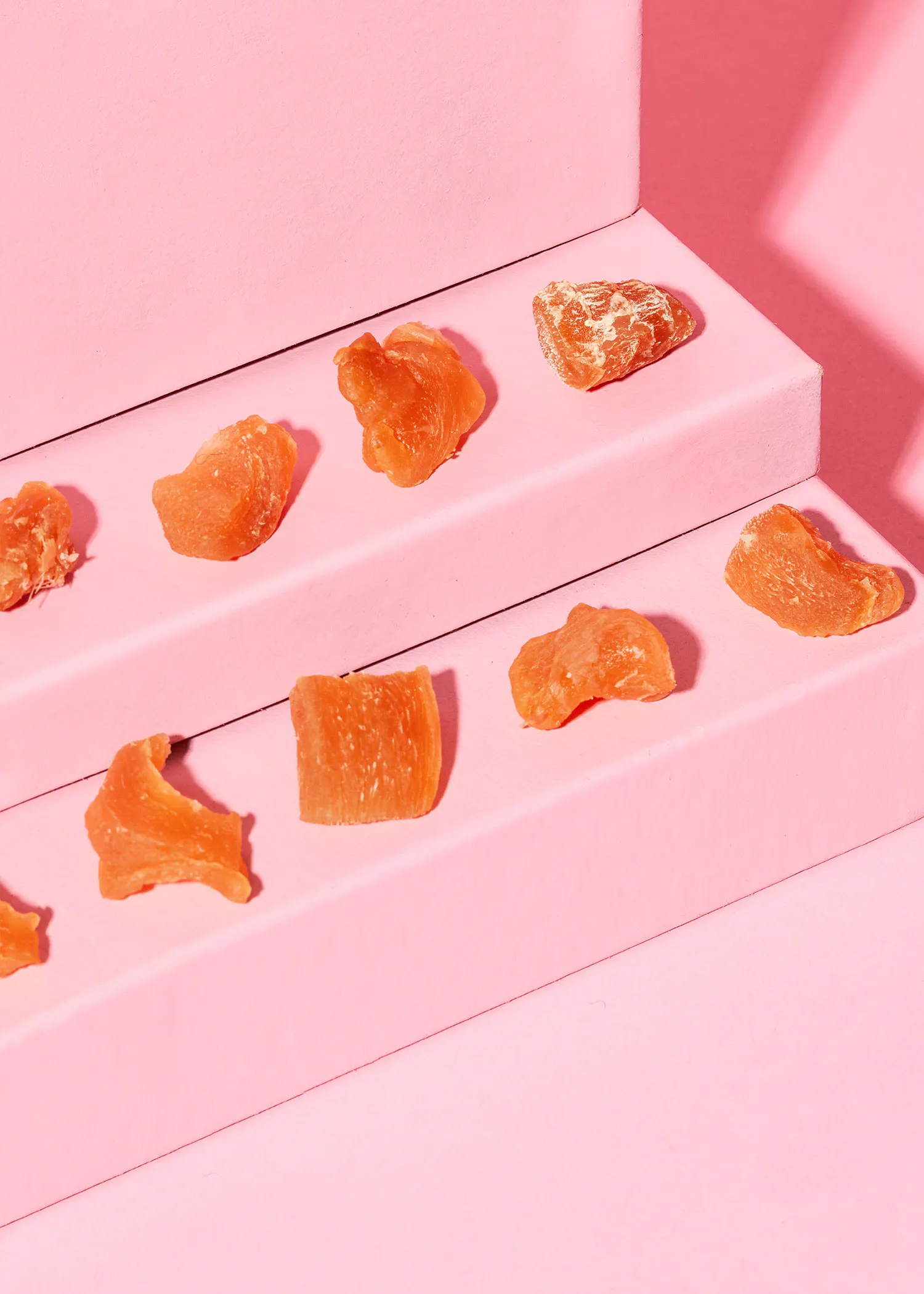 several pieces of dried fruit are on a pink surface