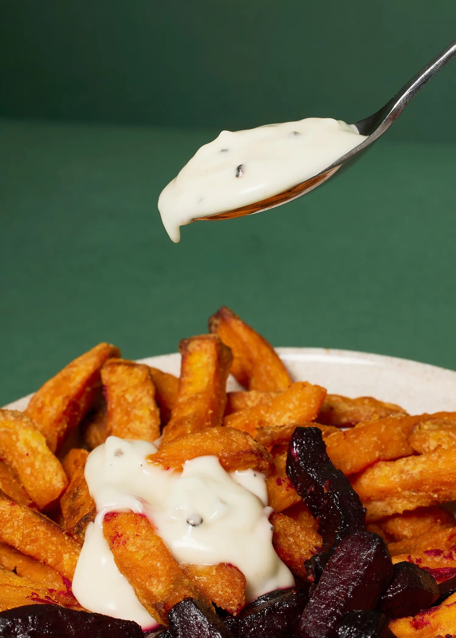 une cuillère remplie de sauce sur une assiette de frites