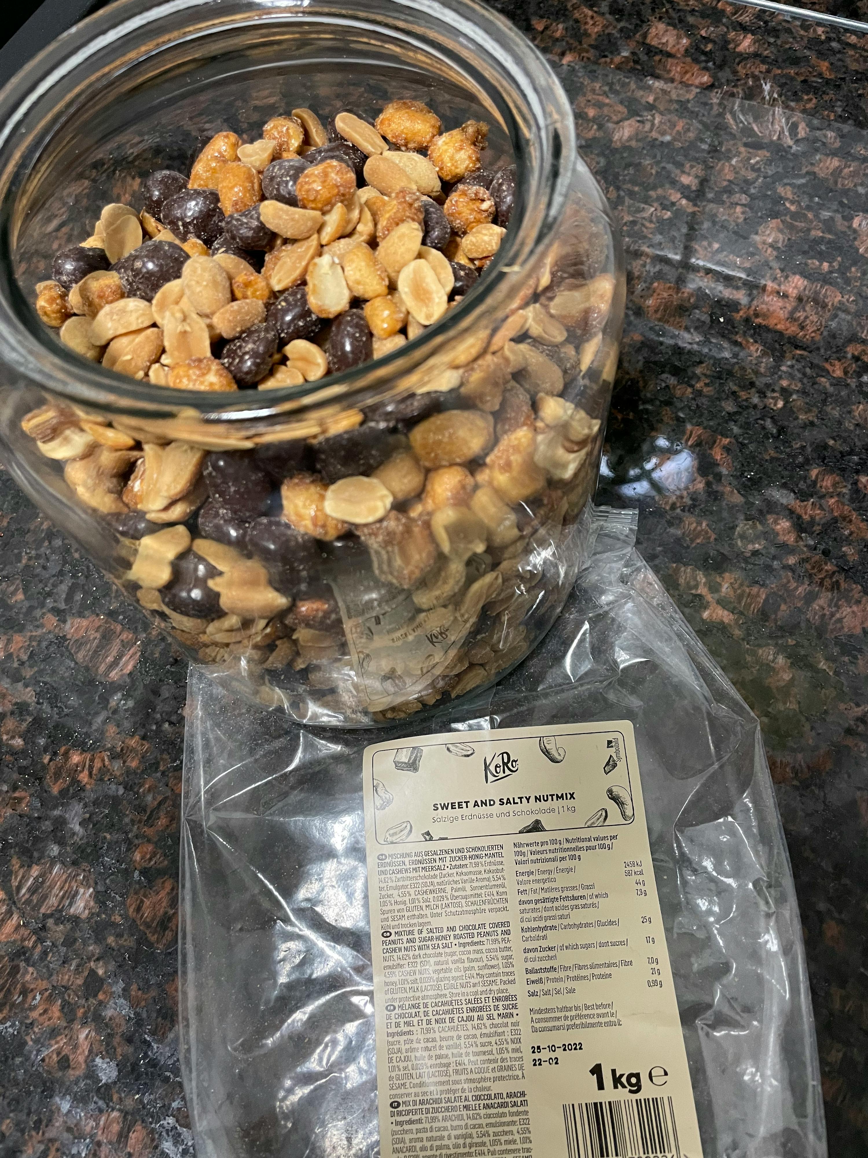 ein Glas gefüllt mit Erdnüssen neben einem Plastikbeutel