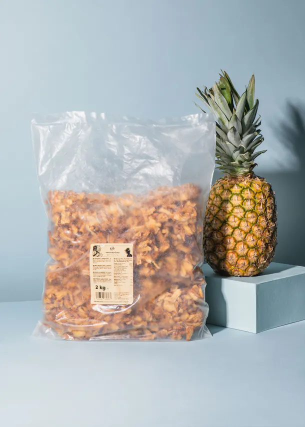 a bag of pineapple chips sits on a table next to a pineapple