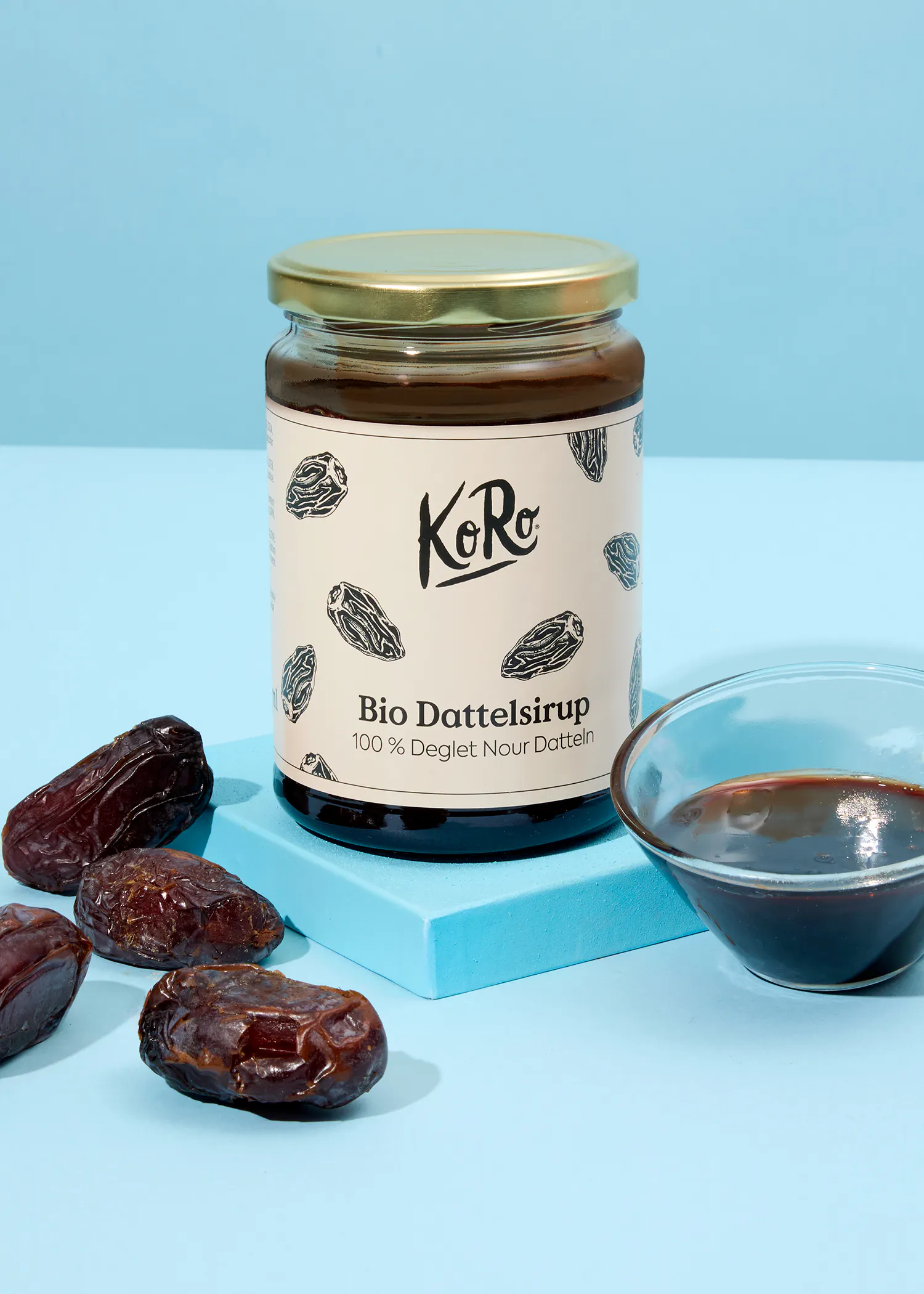 une bouteille de sirop de dattes bio avec des dattes à côté