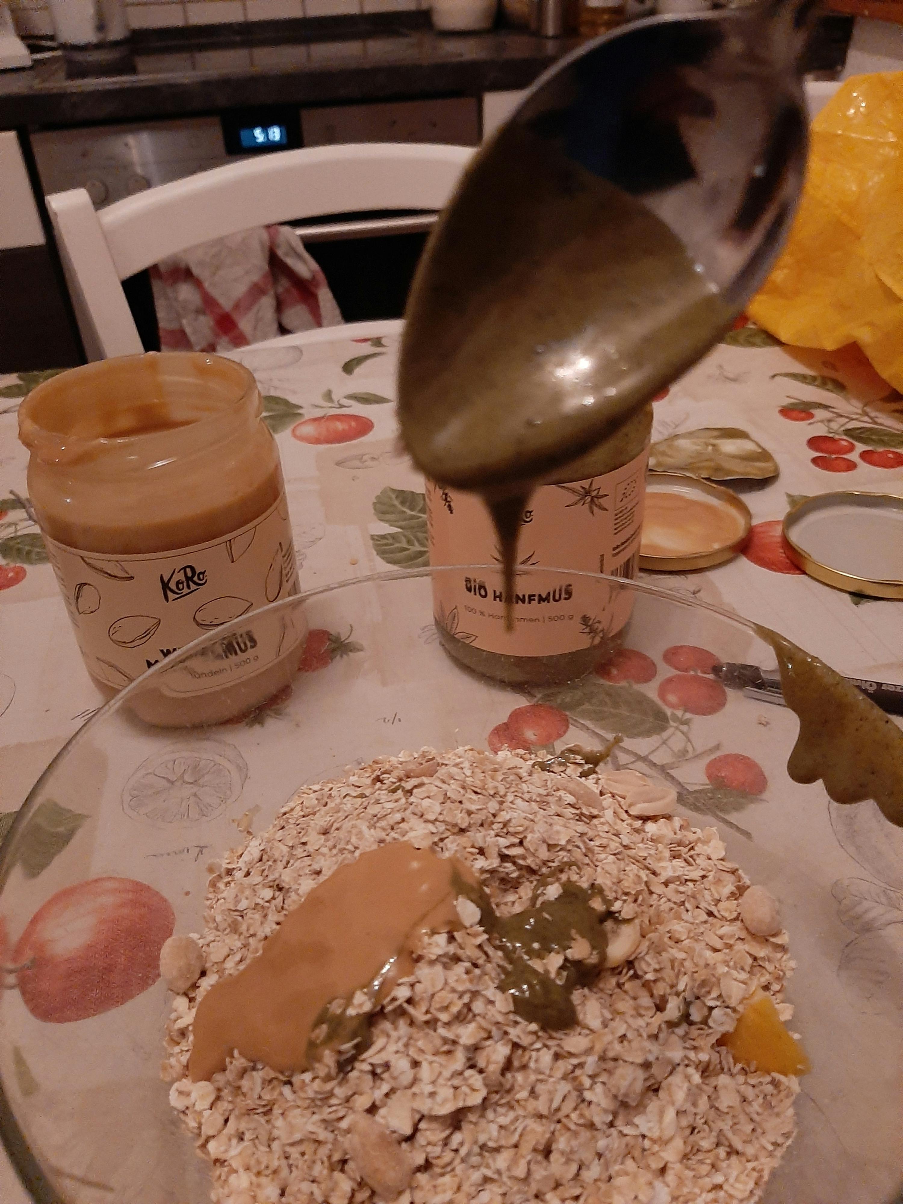 a jar of peanut butter sits on a table next to a bowl of oats