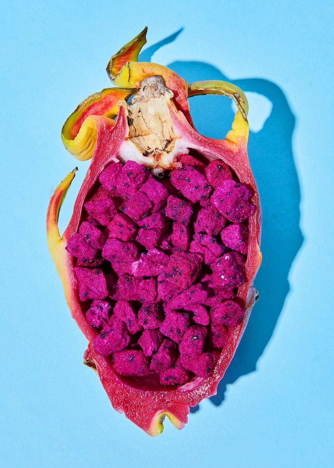 le fruit du dragon est coupé en deux et recouvert de graines violettes