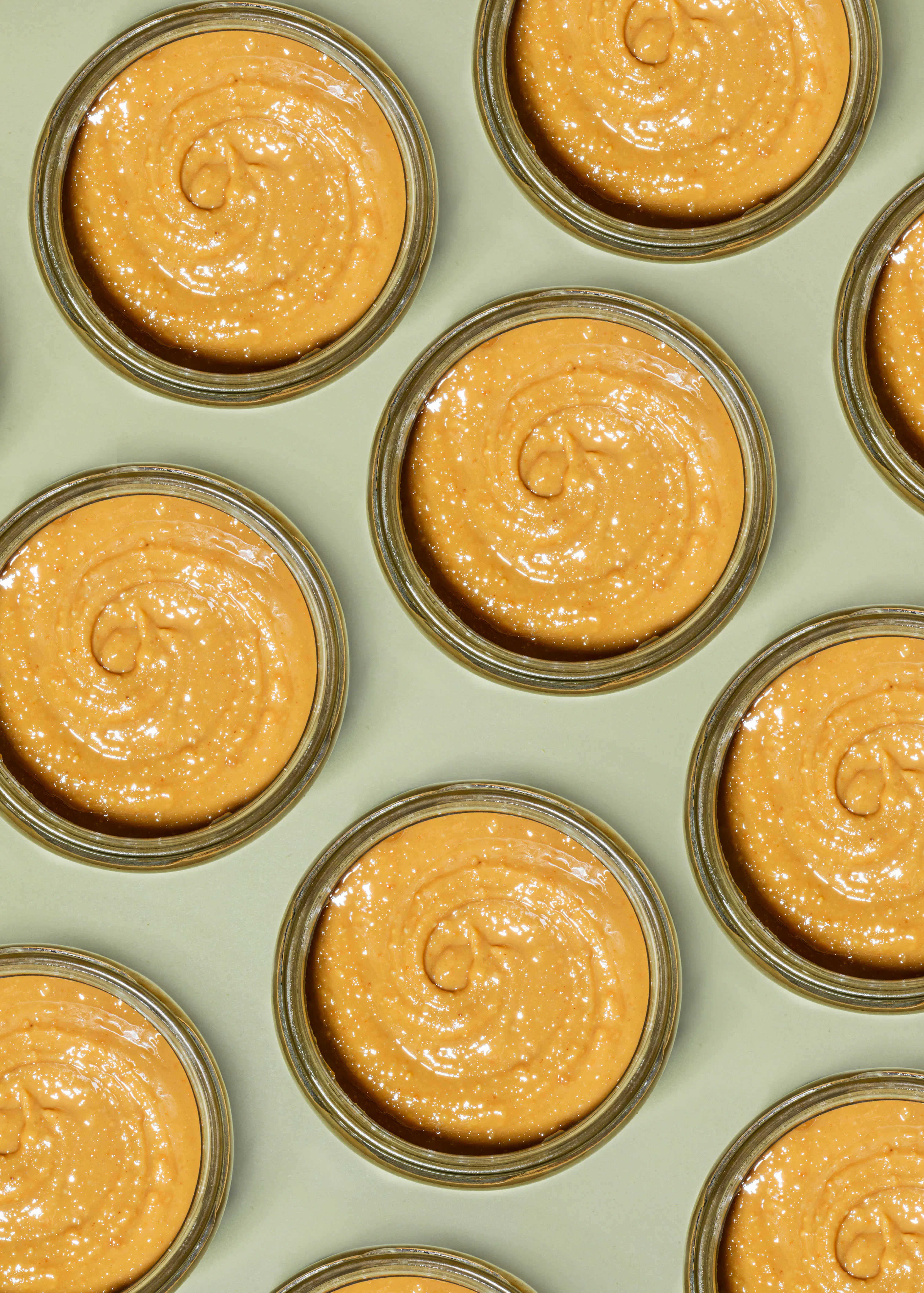 several bowls of peanut butter are lined up on a green surface