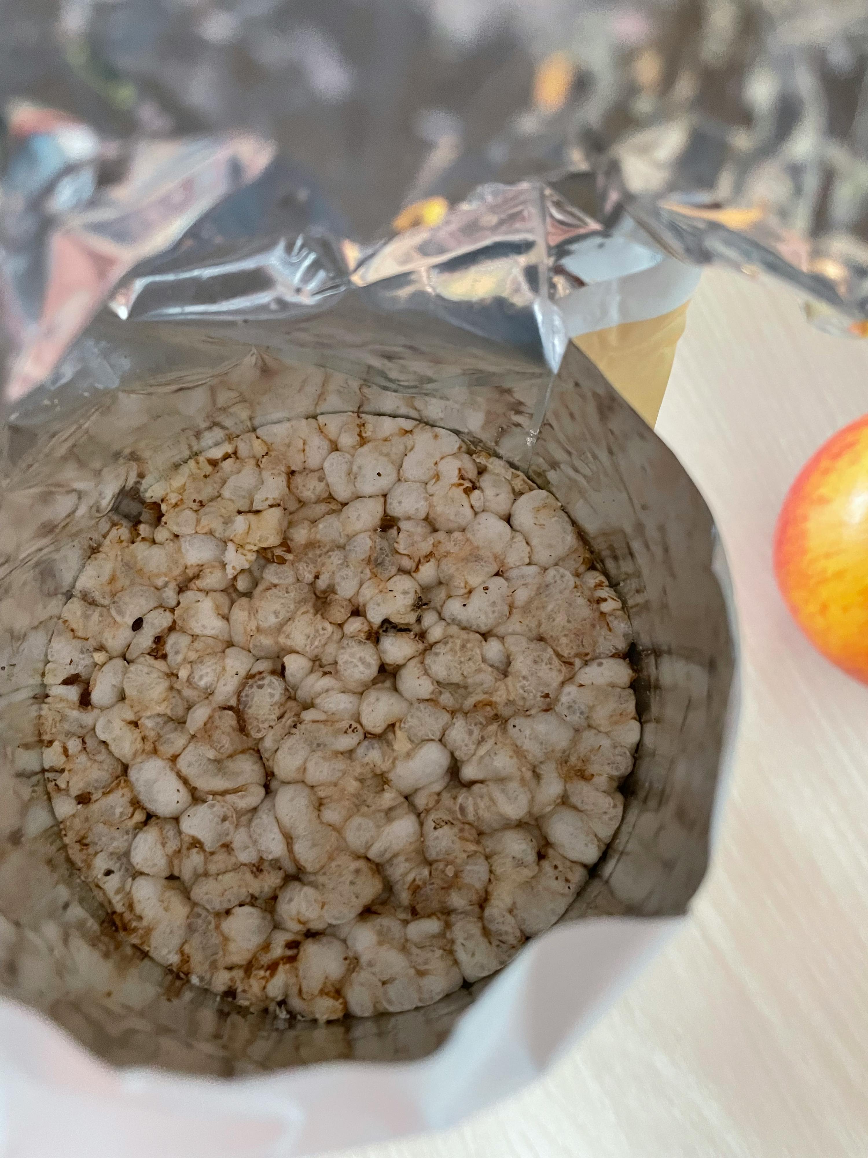une pomme est assise sur une table à côté d' un sac de céréales