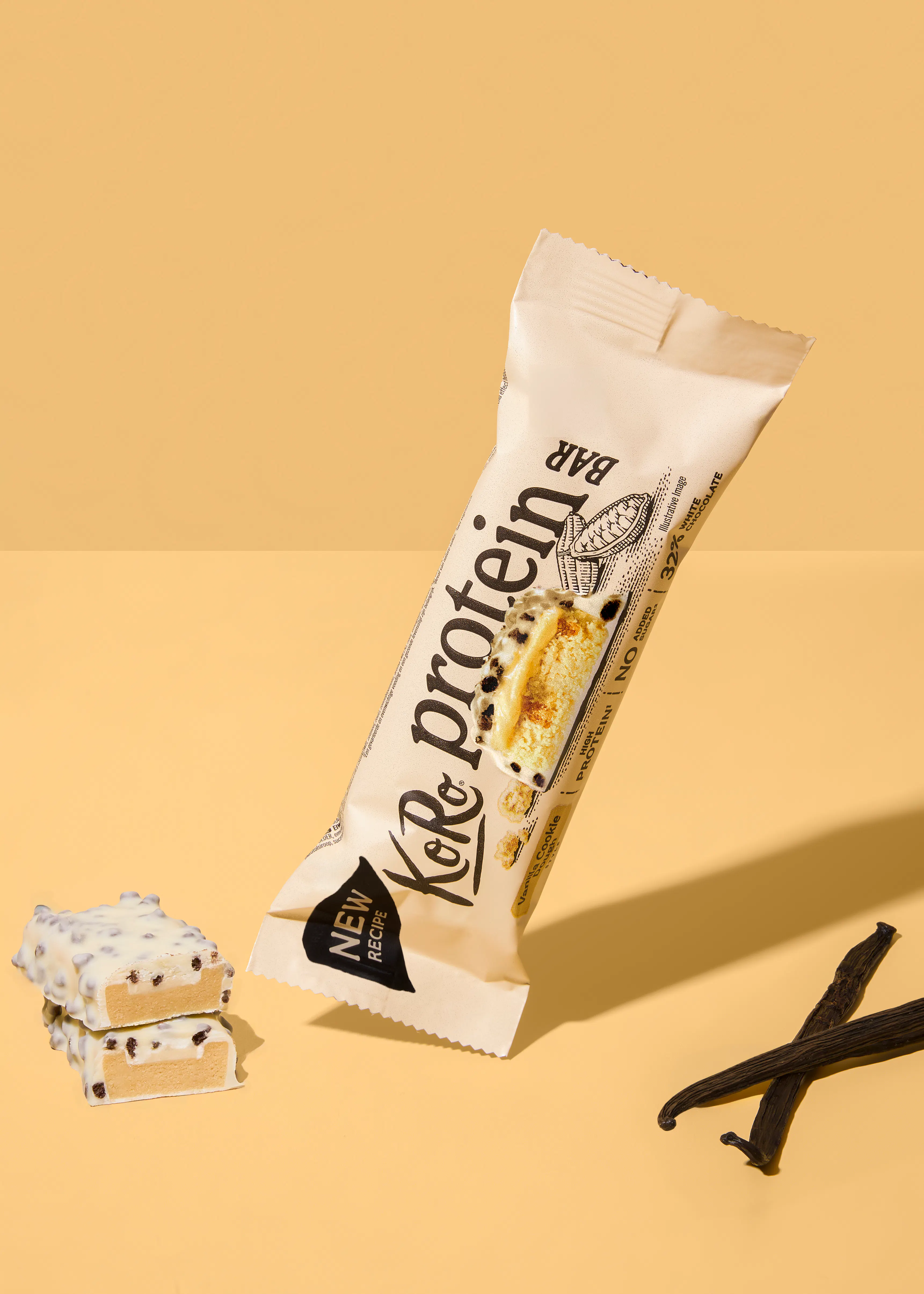 ein schräg liegender koro proteinriegel in vanille-cookie-geschmack mit weißer schokolade, daneben zwei angeschnittene riegelstücke und zwei vanilleschoten auf gelbem hintergrund.