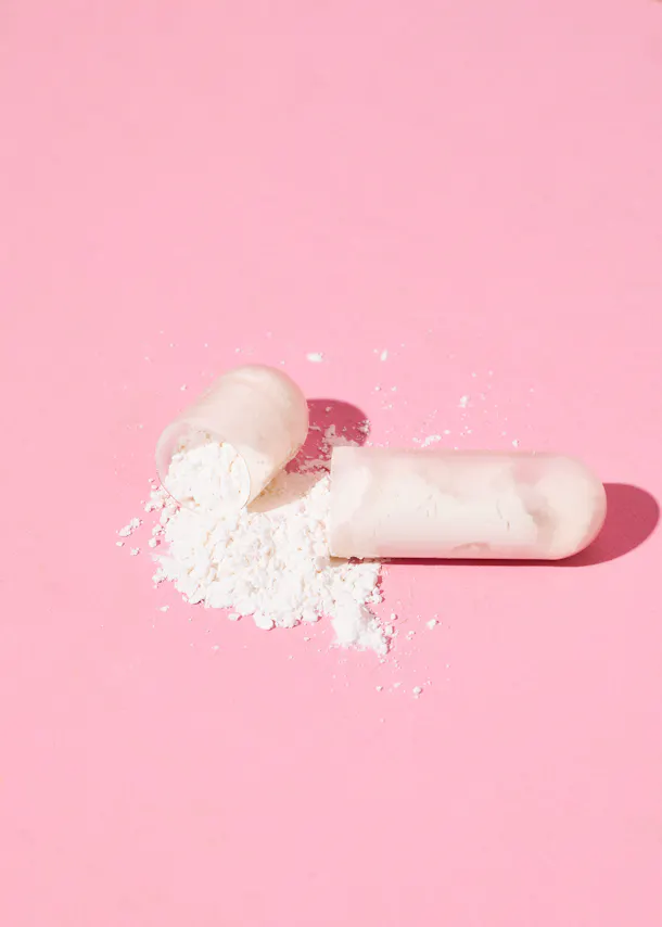 a candy cane with powder coming out of it on a pink surface