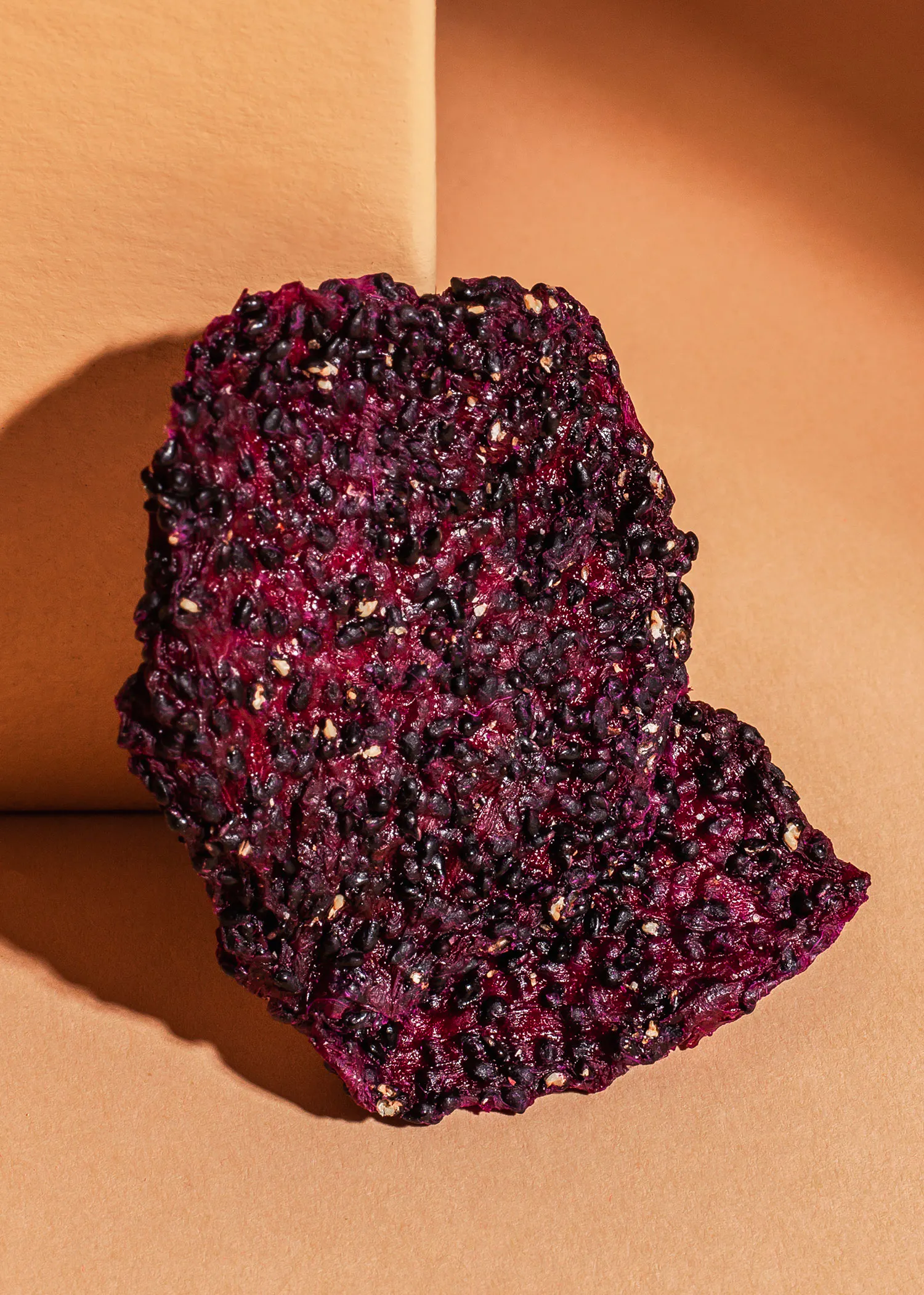 ein Stück lila und schwarzes Essen sitzt auf einem braunen Tisch