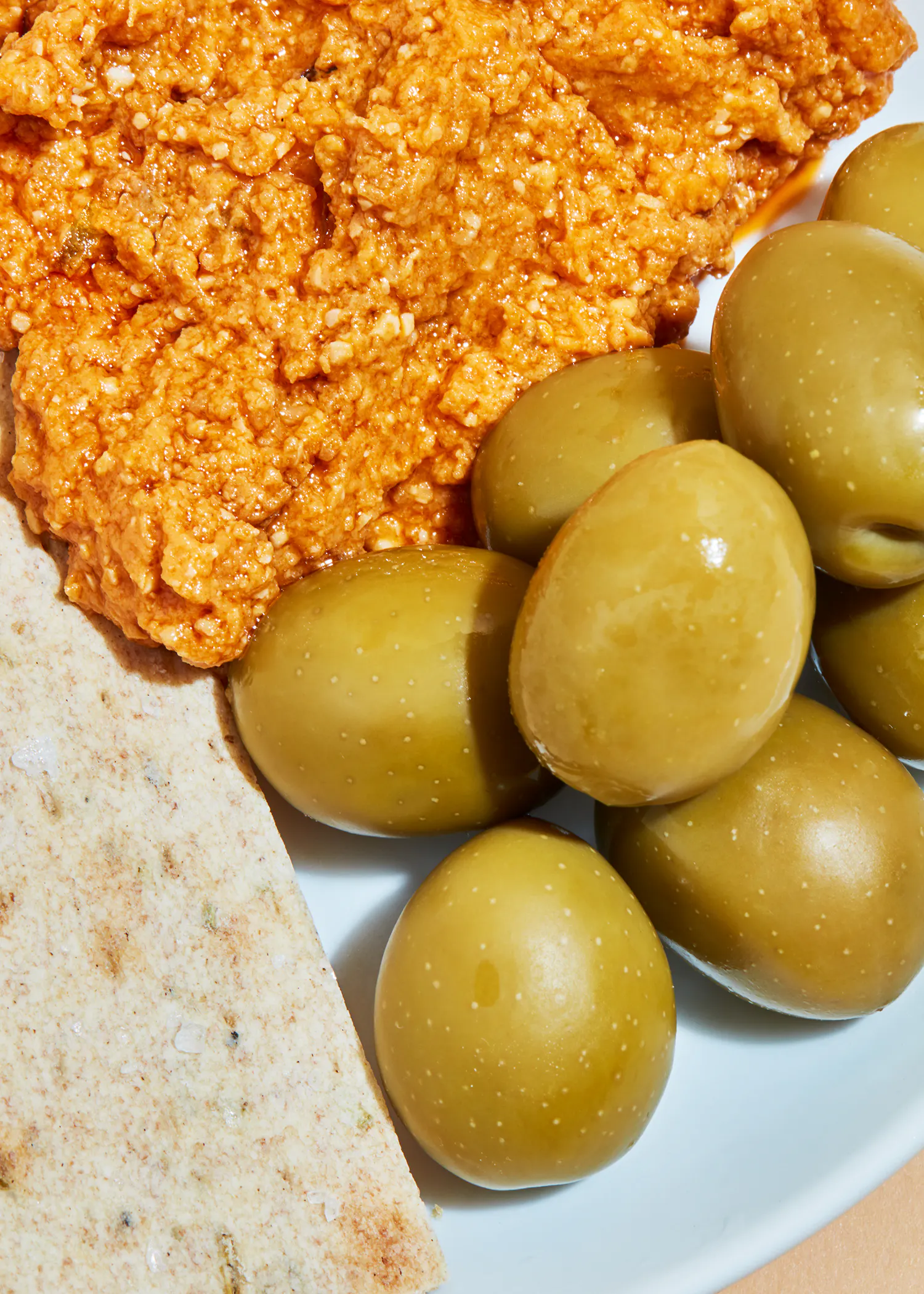 a plate of olives next to a piece of bread