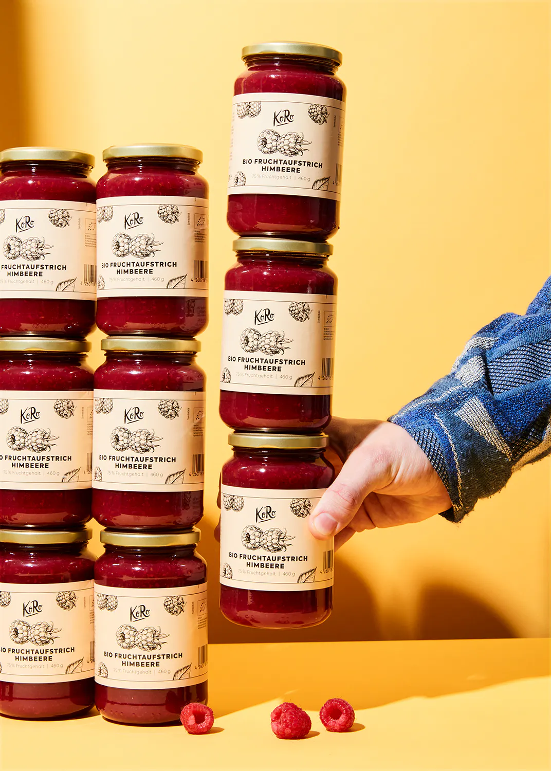 eine Person hält eine Reihe von Gläsern mit Himbeermarmelade in ihren Händen