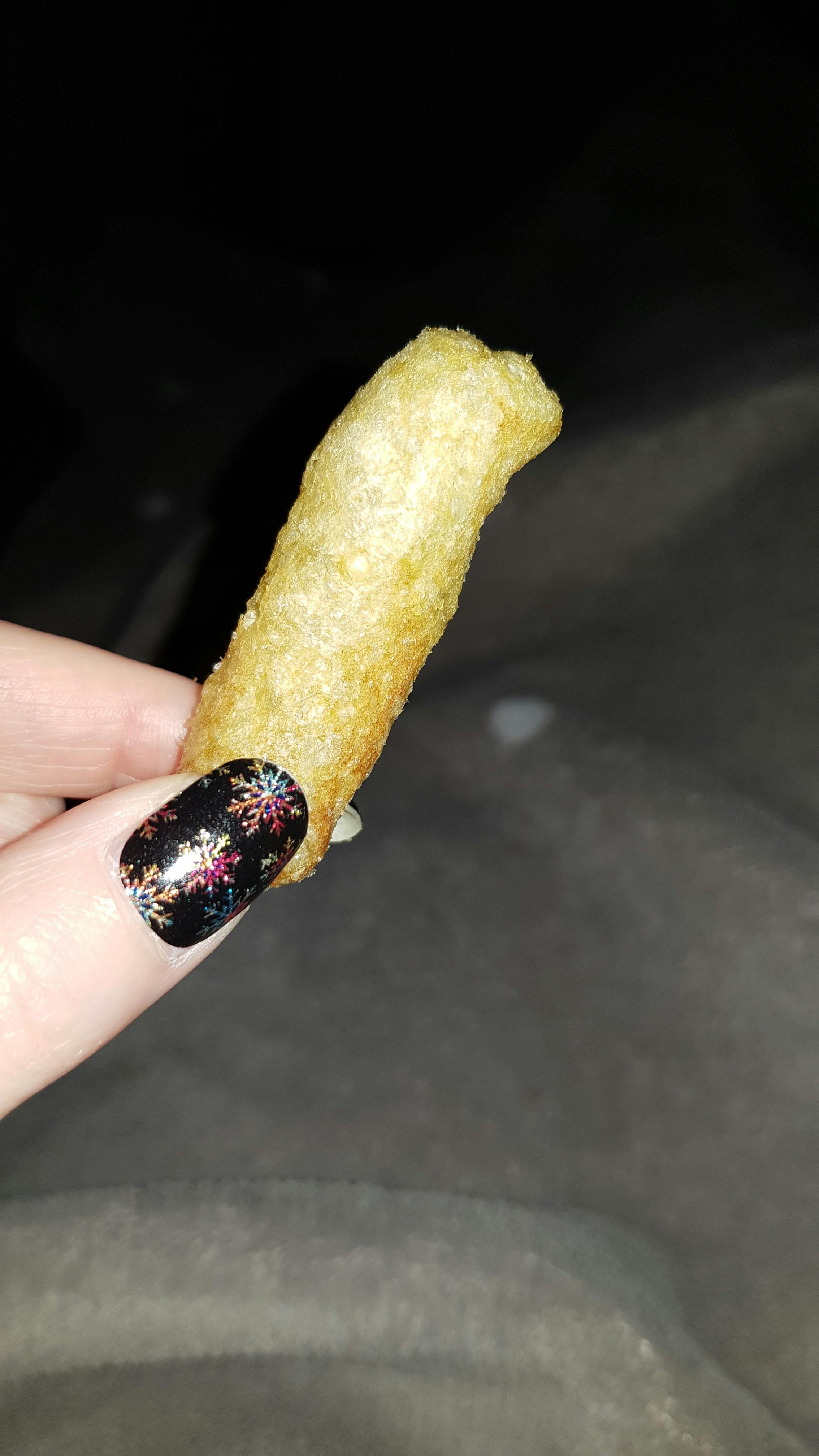 eine Person mit schwarzen Nägeln hält einen Stück Essen