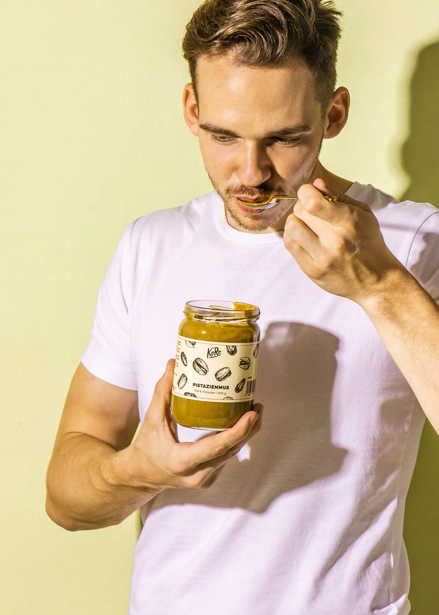 un homme mange de la nourriture avec une cuillère et un pot de nourriture à la main