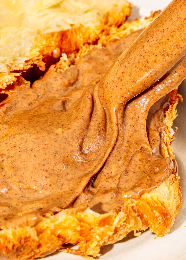eine Person gießt Erdnussbutter auf ein Stück Brot