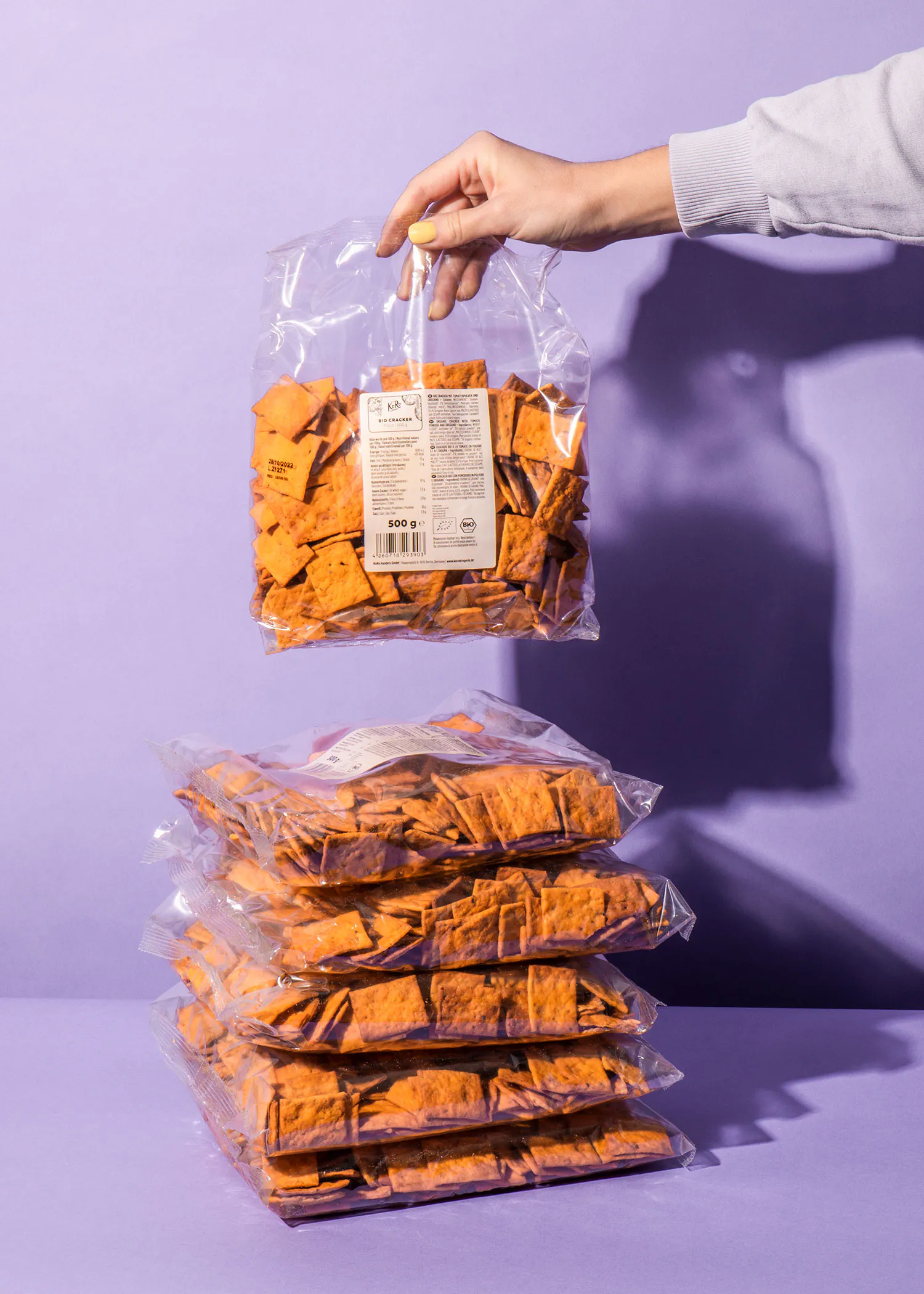 a person is holding a bag of tortilla chips over a stack of tortilla chips