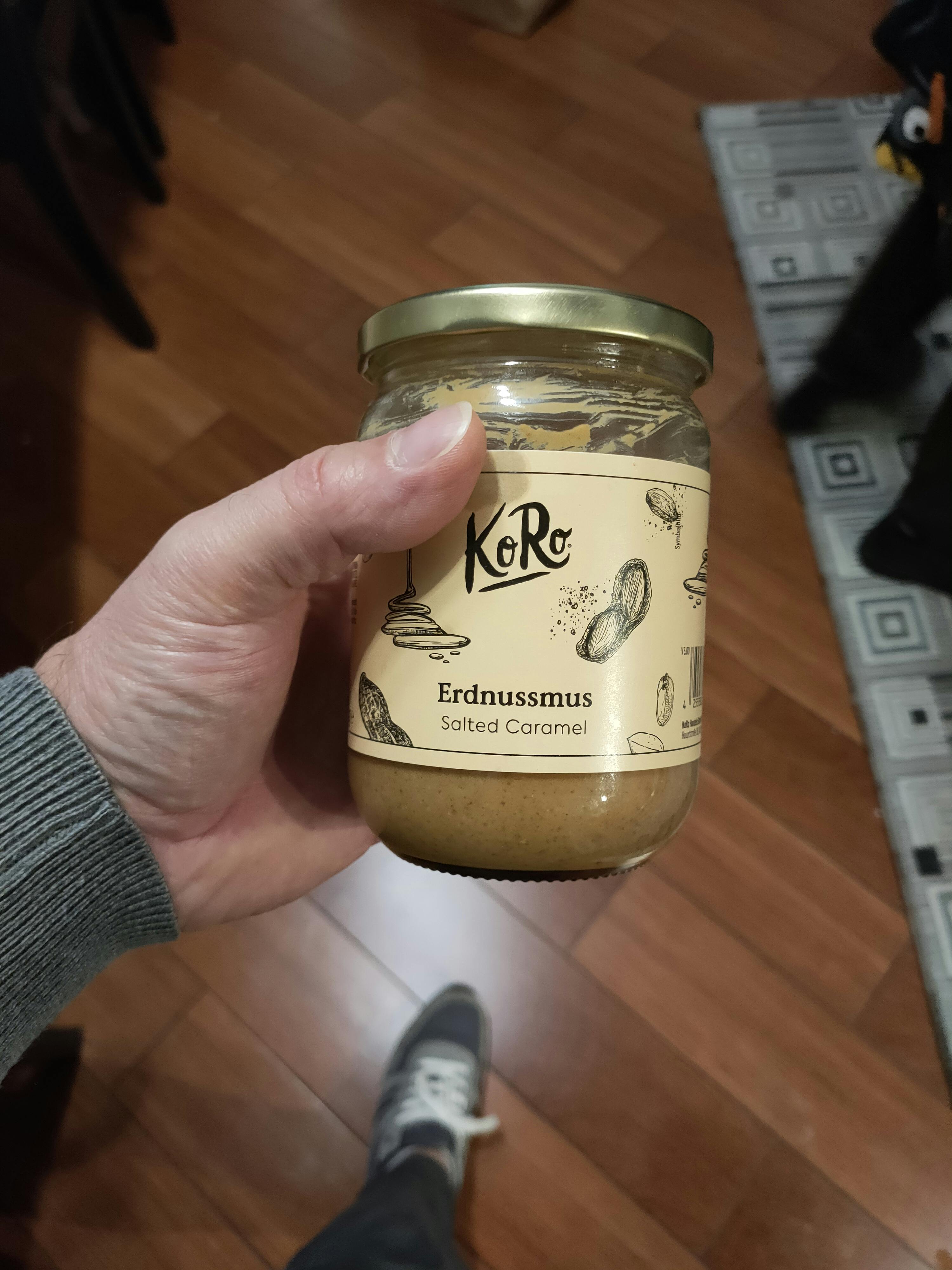 a person holding a jar of koro erdnussmus salted caramel