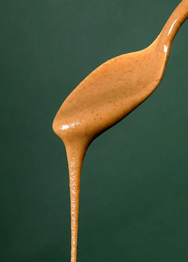 un gros plan d' une cuillère remplie de sauce sur fond vert