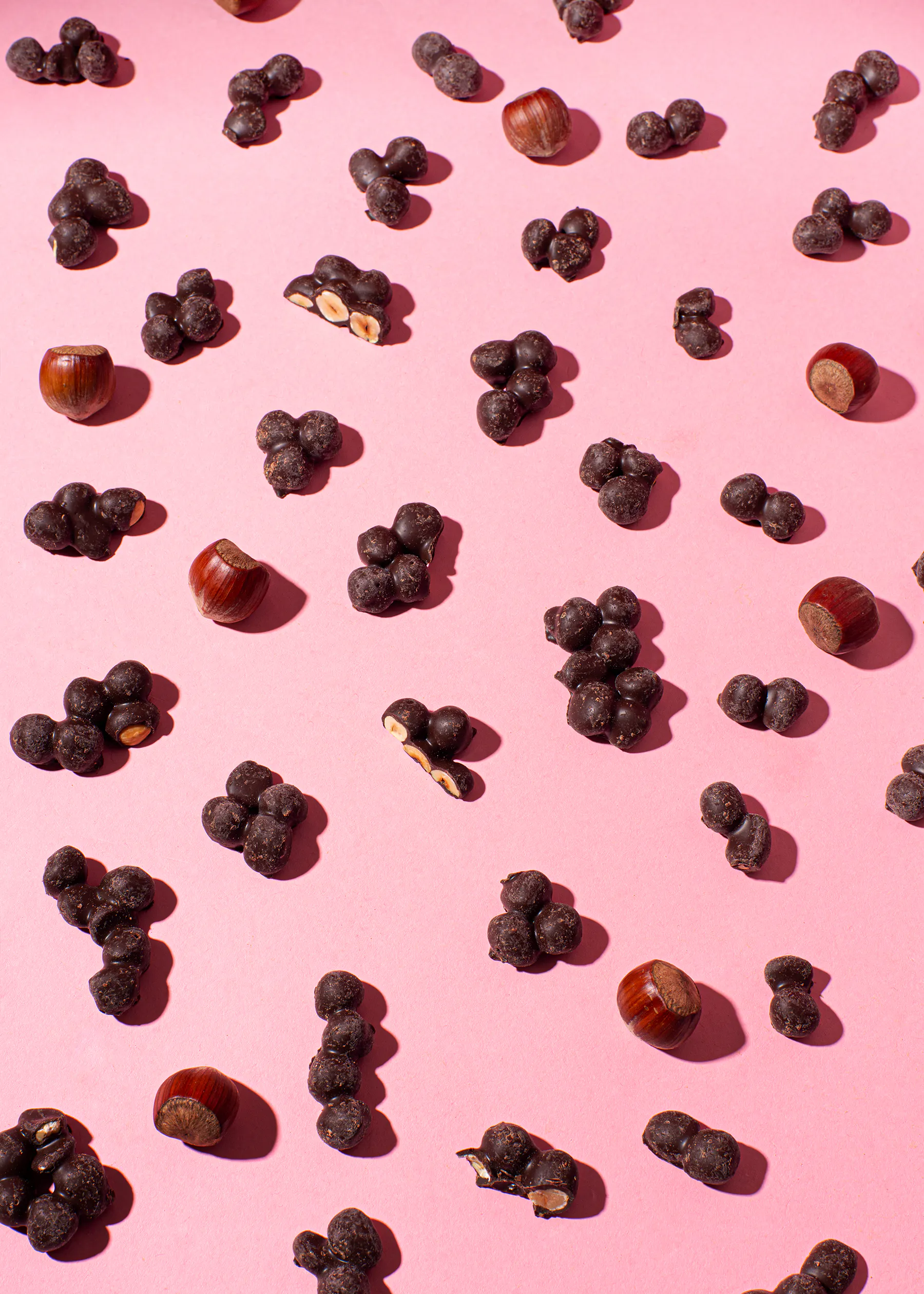 un motif de noisettes et de noix enrobées de chocolat sur fond rose