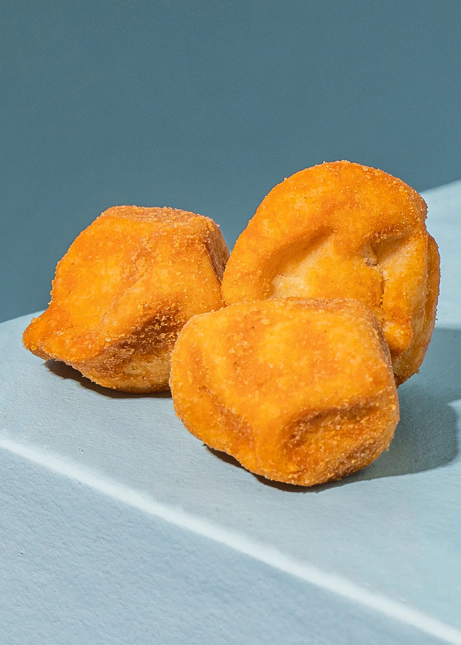 trois beignets frits sont posés sur une surface blanche