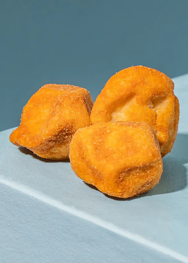 trois beignets frits sont posés sur une surface blanche