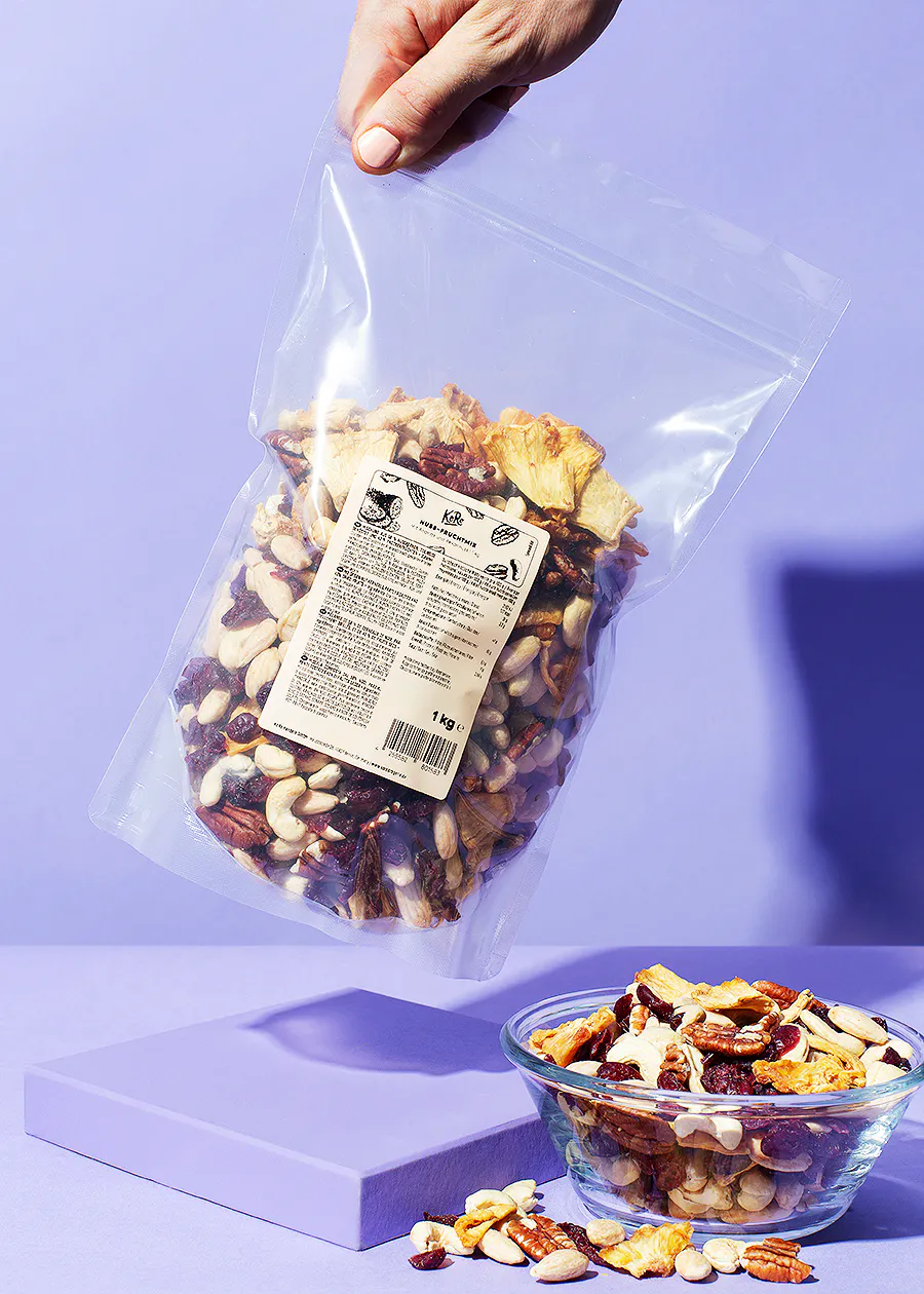 eine Person hält einen Plastikbeutel mit Nüssen und trockenfrüchten in der Hand