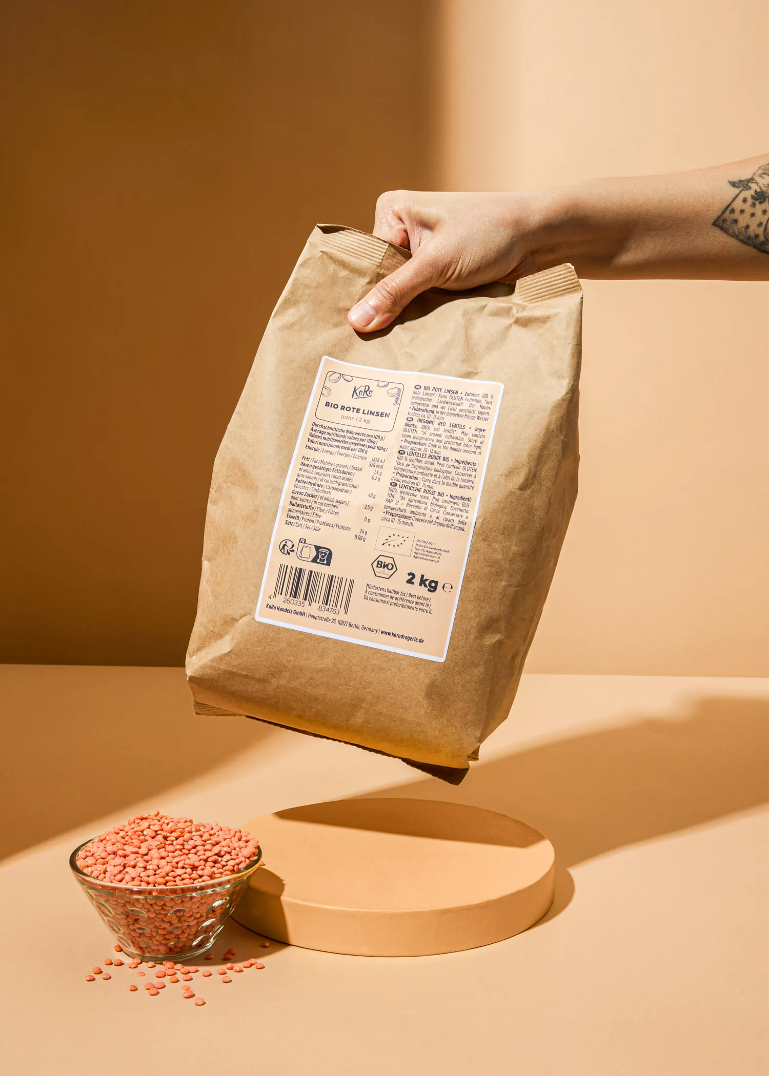 une personne tient un sac de lentilles rouges de 2 kg