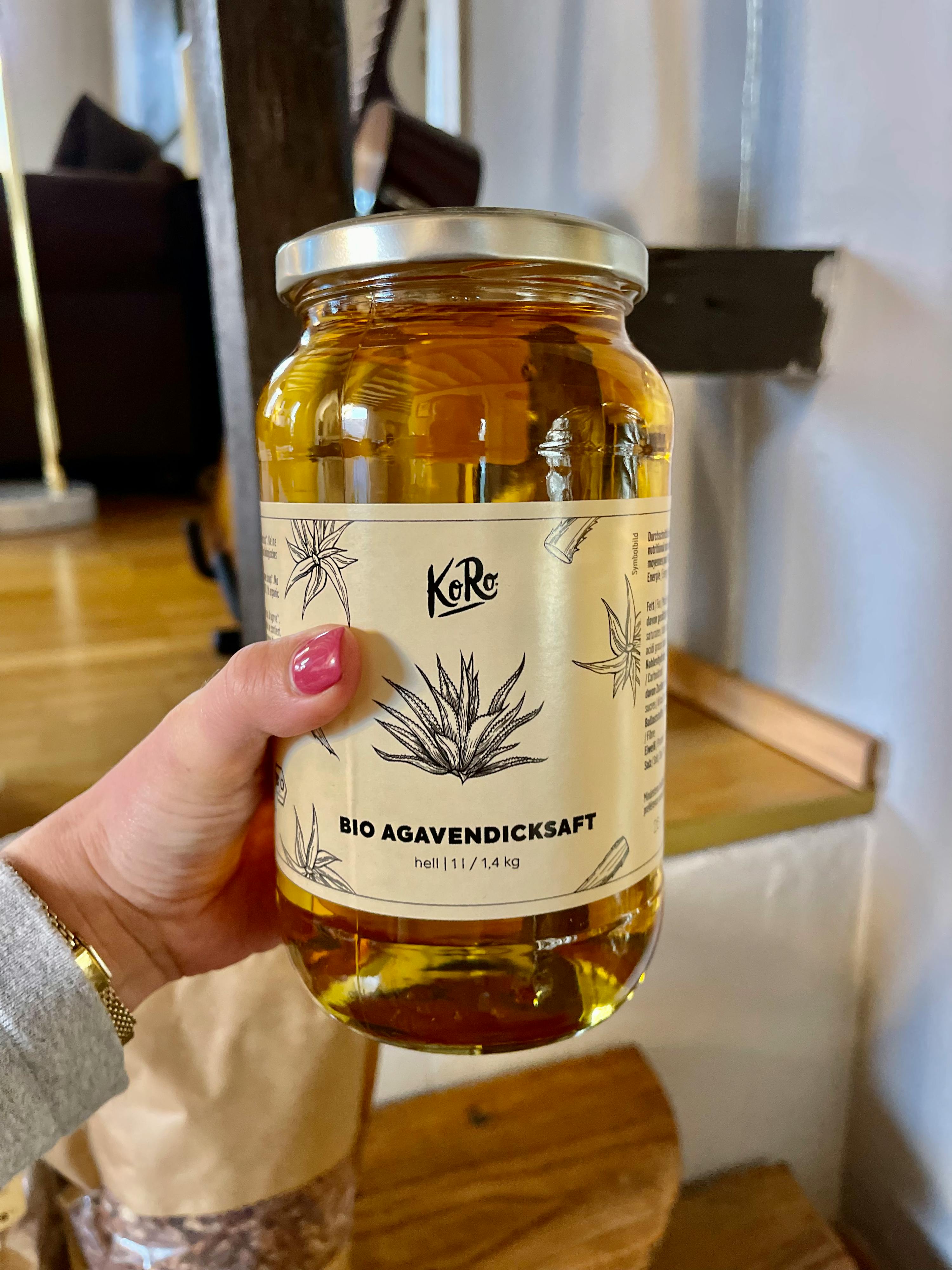 a person is holding a jar of bio agavendicksaft in their hand