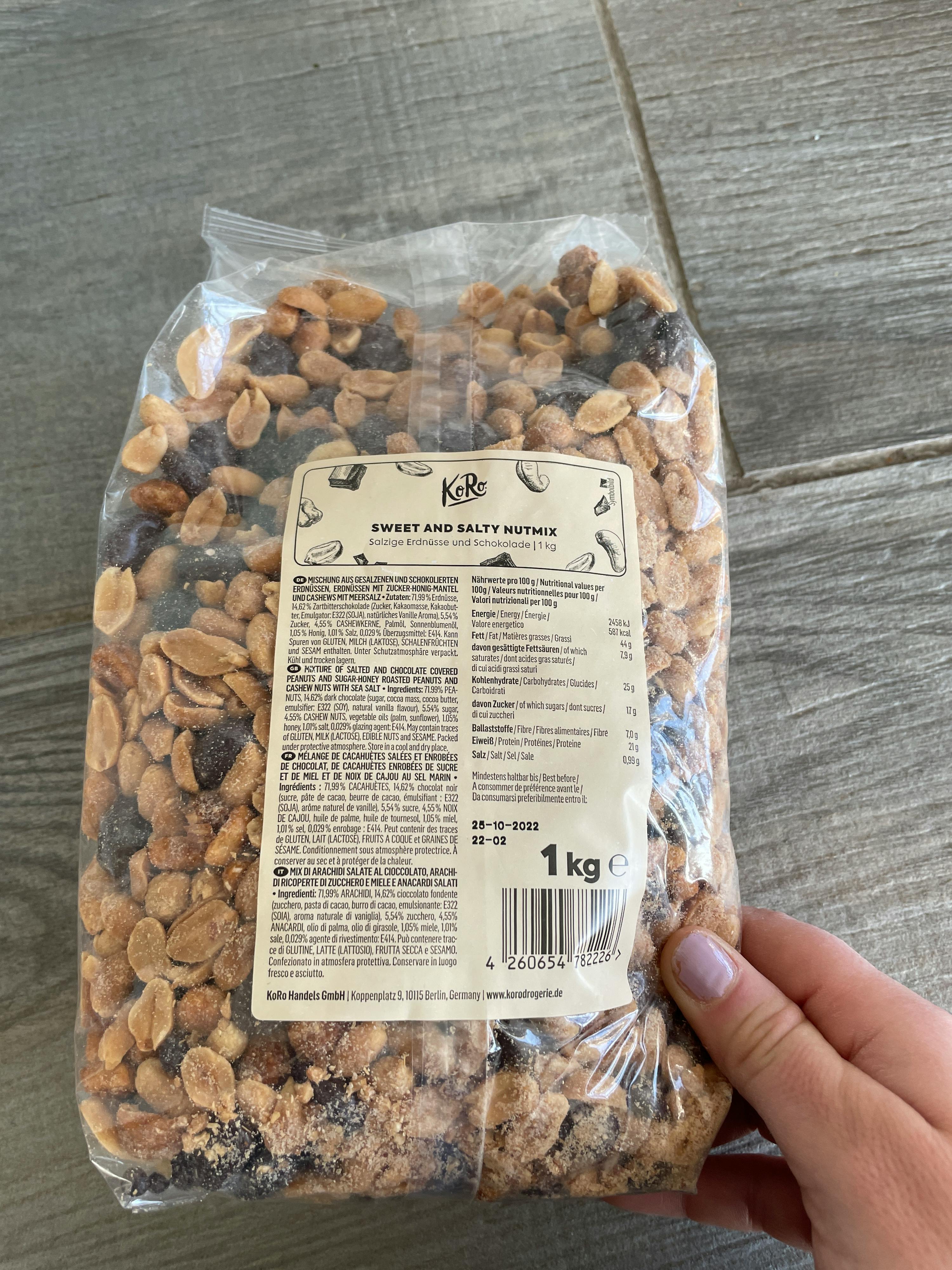 eine Person hält eine Tüte süße und salzige Erdnüsse in der Hand