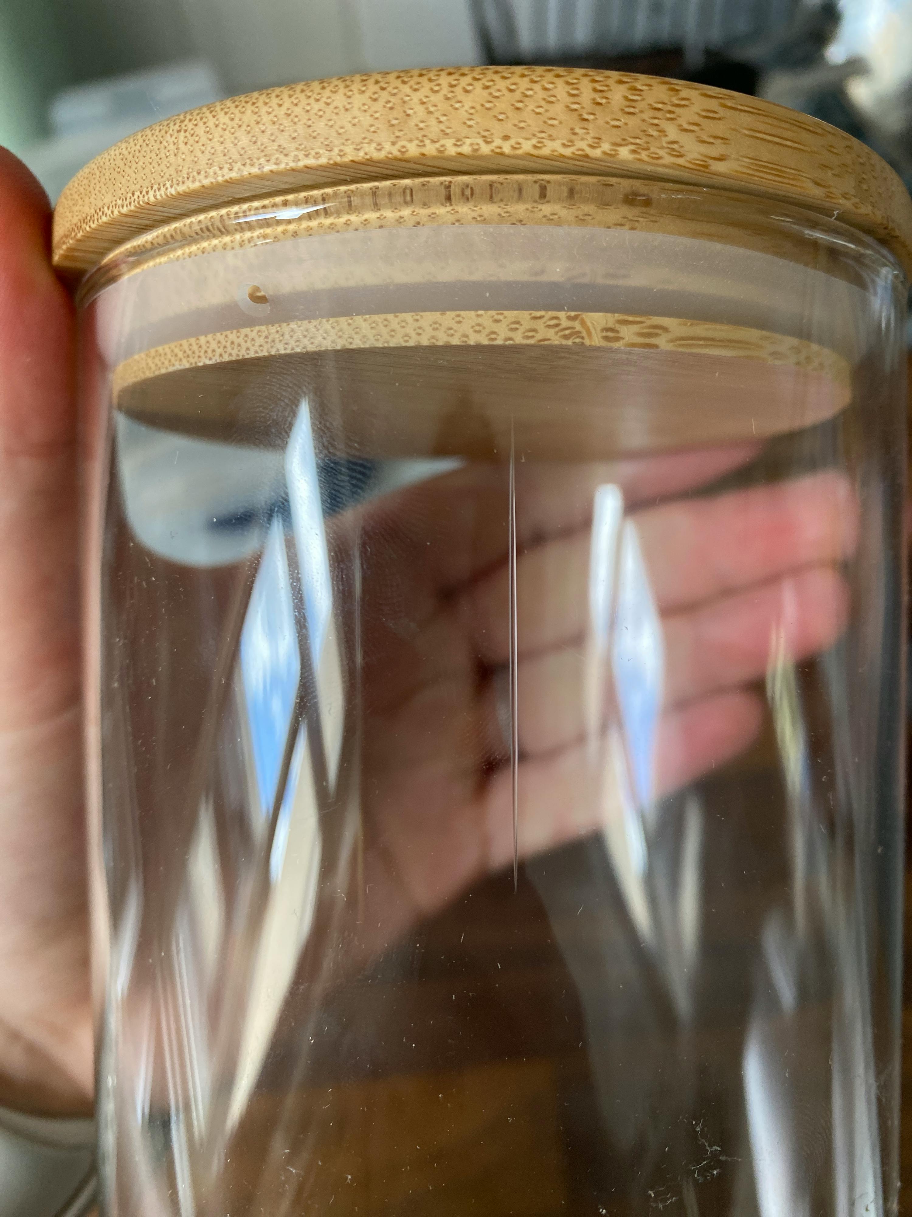 una persona tiene in mano un barattolo di vetro con un coperchio in legno