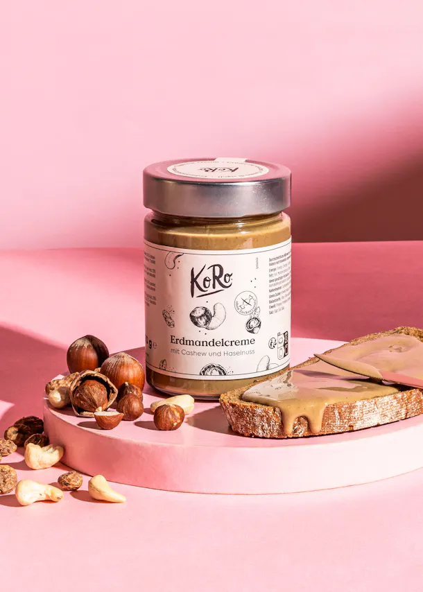 une bouteille de crème d' amandes est posée sur une table rose à côté d' un morceau de pain