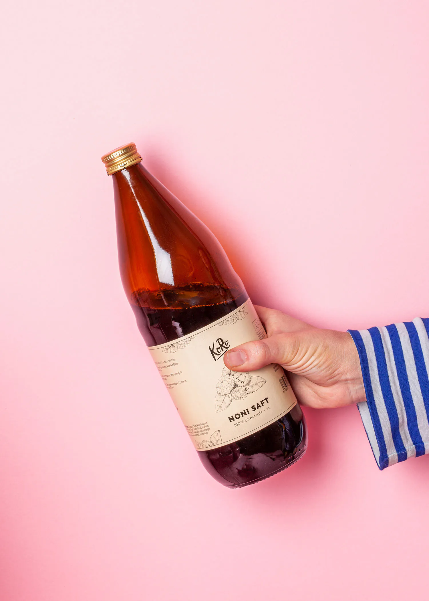 une main tient une bouteille de noni saft